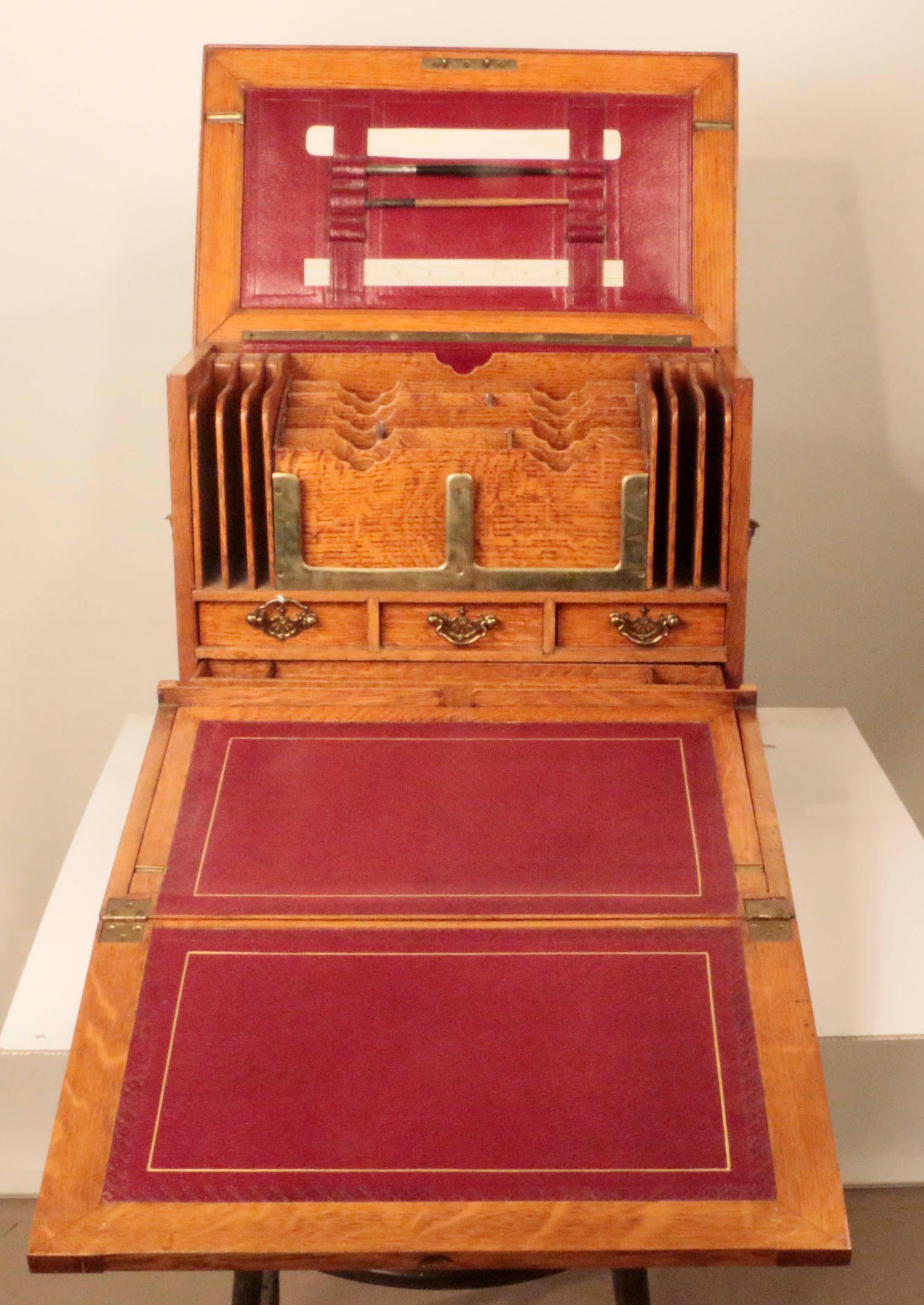 This is a kind of office compactum. Set it down on a table, open it up and start working. The rising top reveals ruler, and pens and the original blotter. As the writing slope is folded out, the red leather and tooled gilt surface comes into view