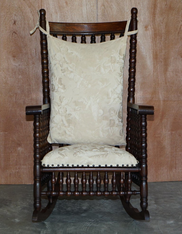 We are delighted to offer for sale absolutely stunning ornately carved with Bobbin turns, Rocking armchair with Cherub stitched upholstery 

This is pretty much the finest rocking chair I have ever seen. Most likely made for and retailed by