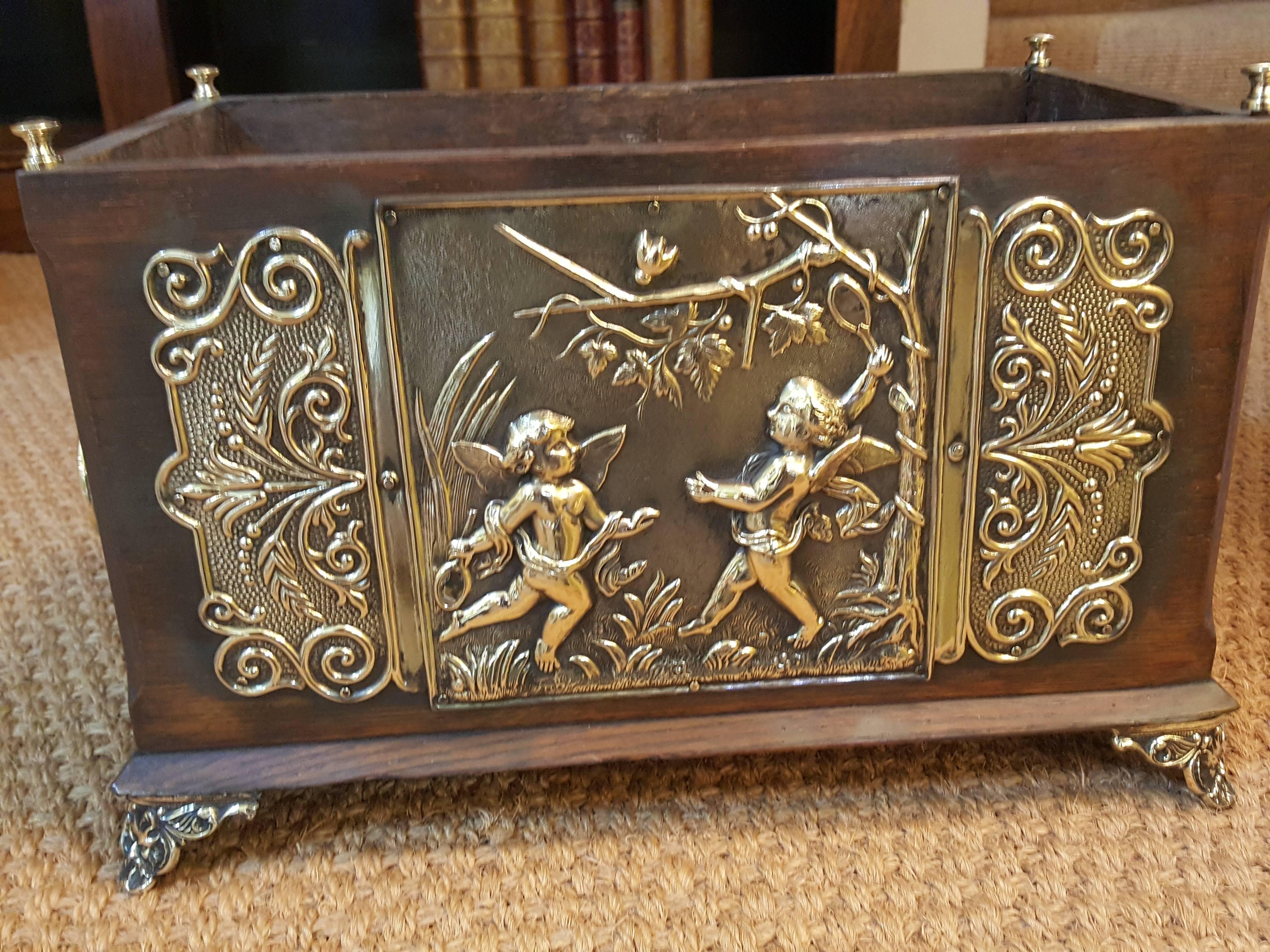 Victorian oak table planter with brass embossed plaques featuring cherubs at play with brass ring handles to the sides.
Measure: 15