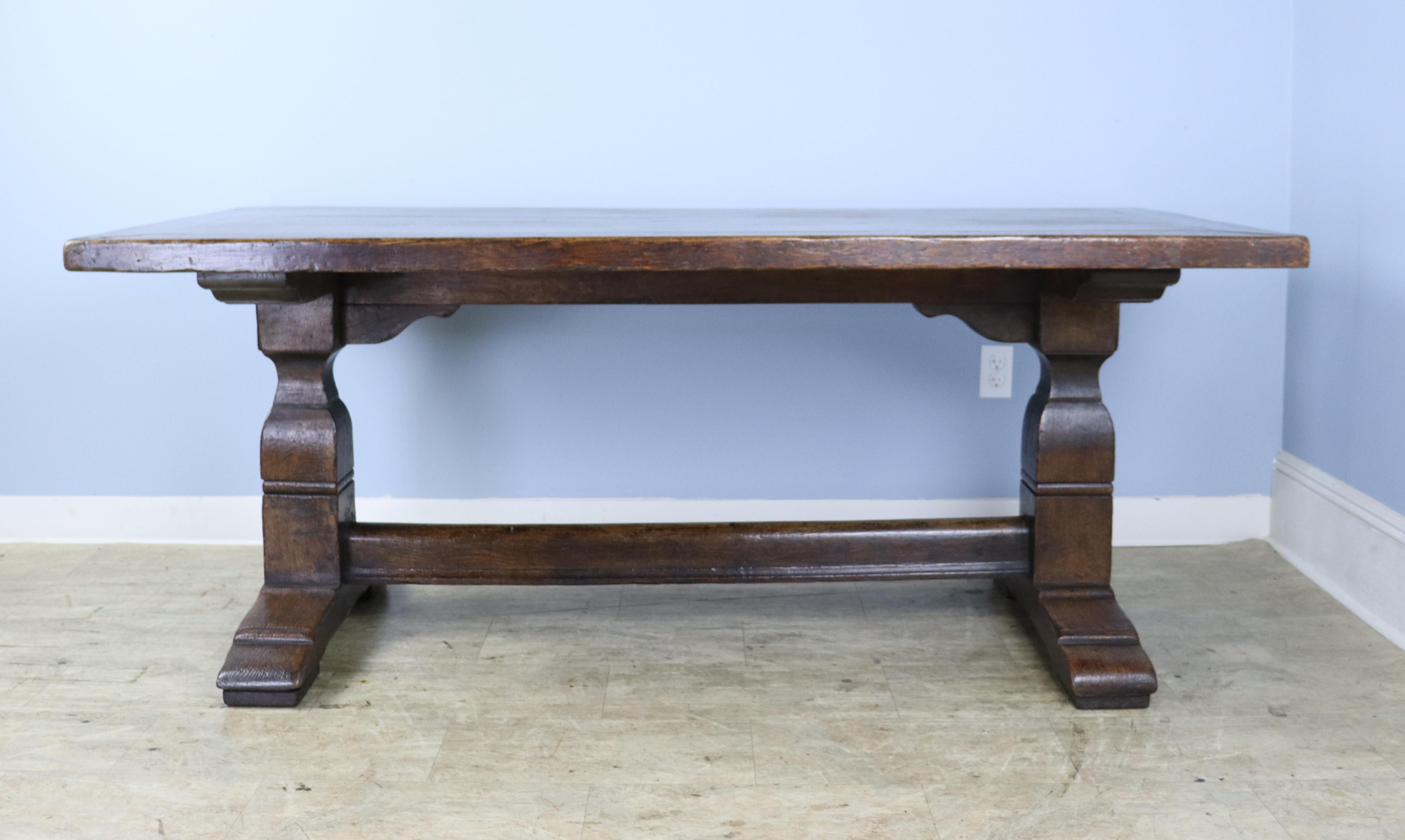 A grand oak trestle table, fashioned in the Victorian era of even older wood. Beautiful grain, color and patina on the top and good decorative base. The top is 2