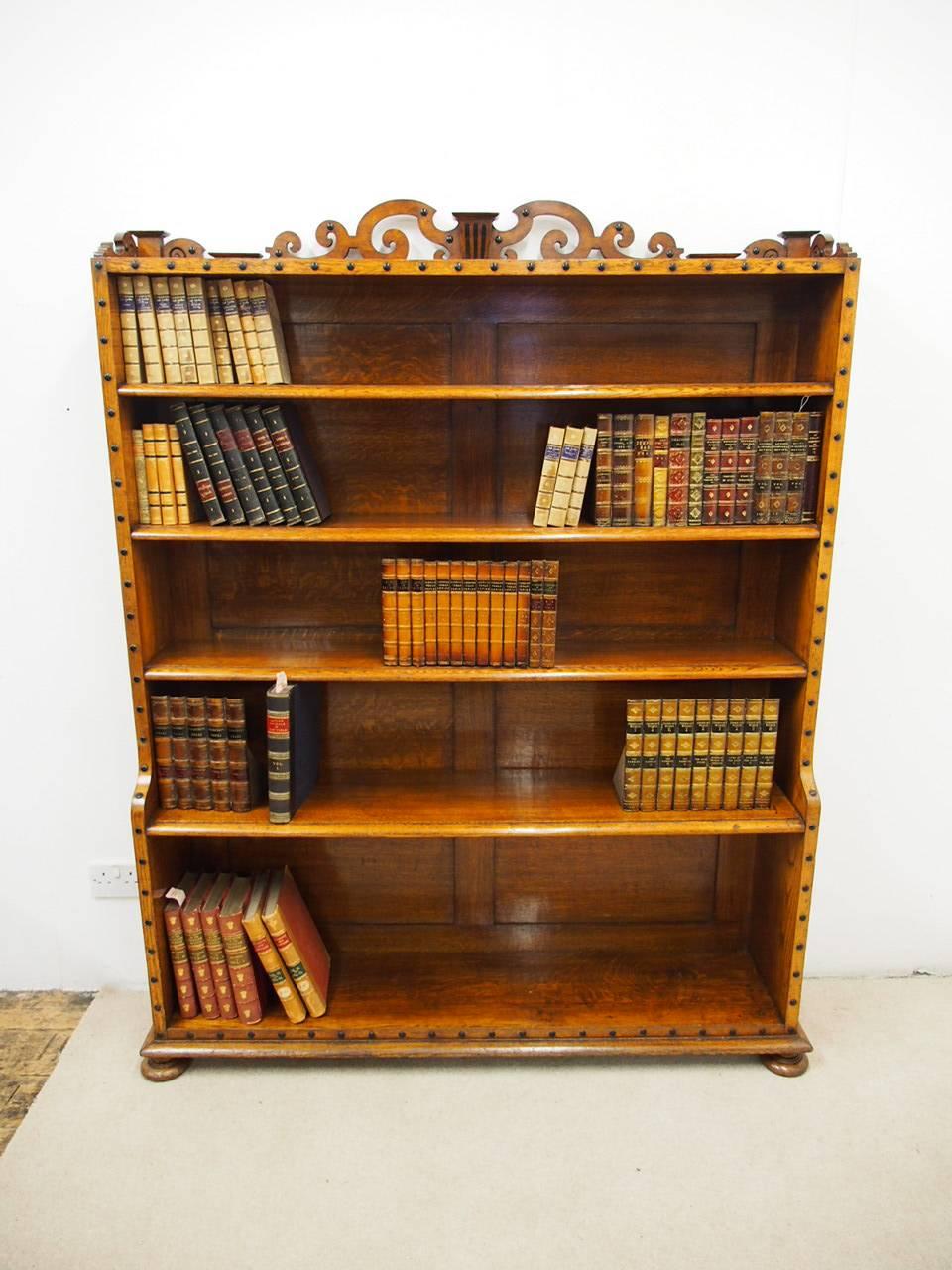 Victorian oak waterfall bookcase in the manner of Richard Bridgens, circa 19th century. The scrolled and pierced crest rail over four graduated shelves, outlined with ebonized bead decoration, raised on flattened bun feet.