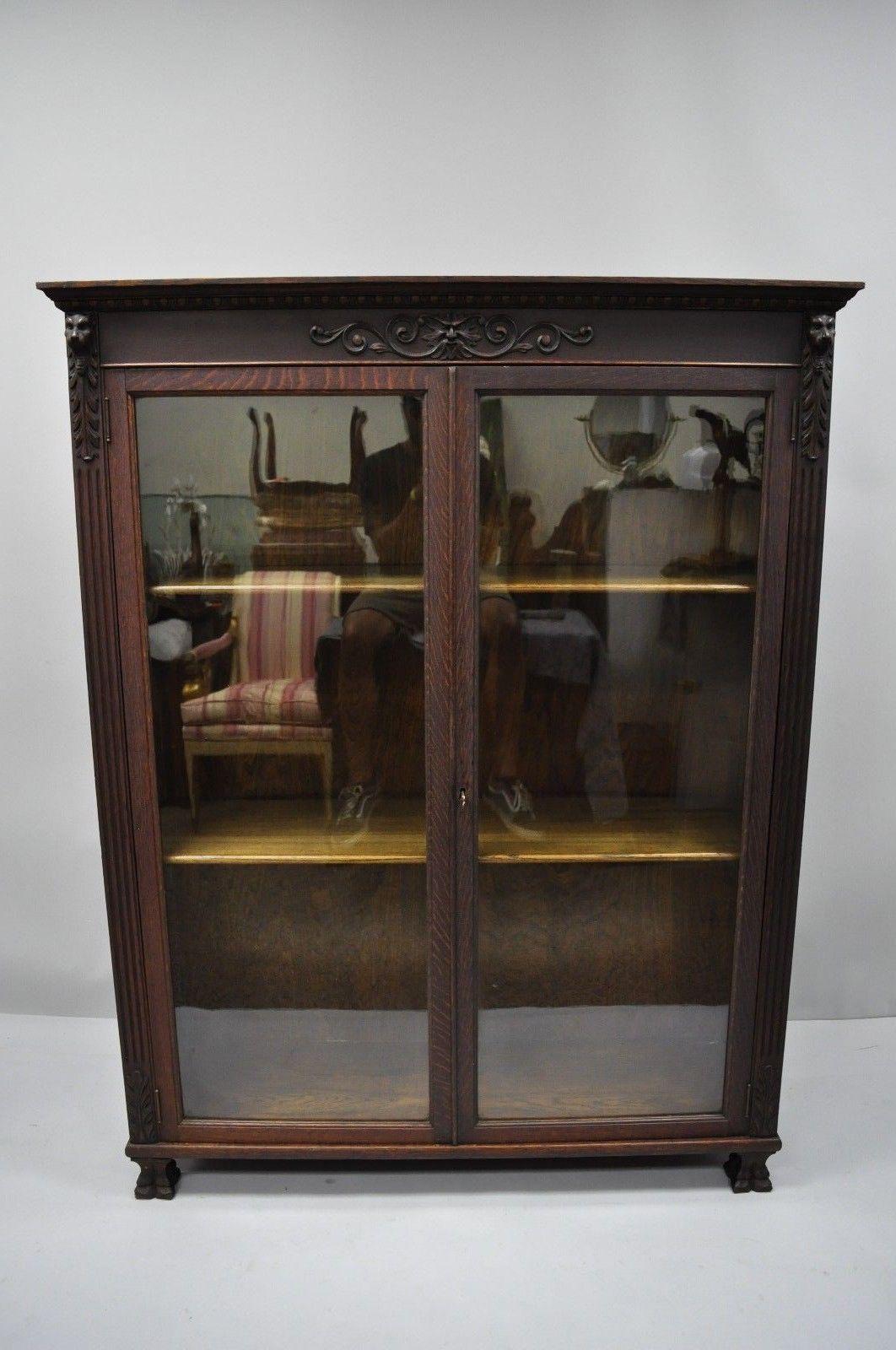 Antique oakwood Victorian glass two door bookcase with claw feet, carved lions, and northwind face. Item features carved claw feet, lion and northwind faces, beautiful wood grain, two glass swing doors, two adjustable wooden shelves, and working