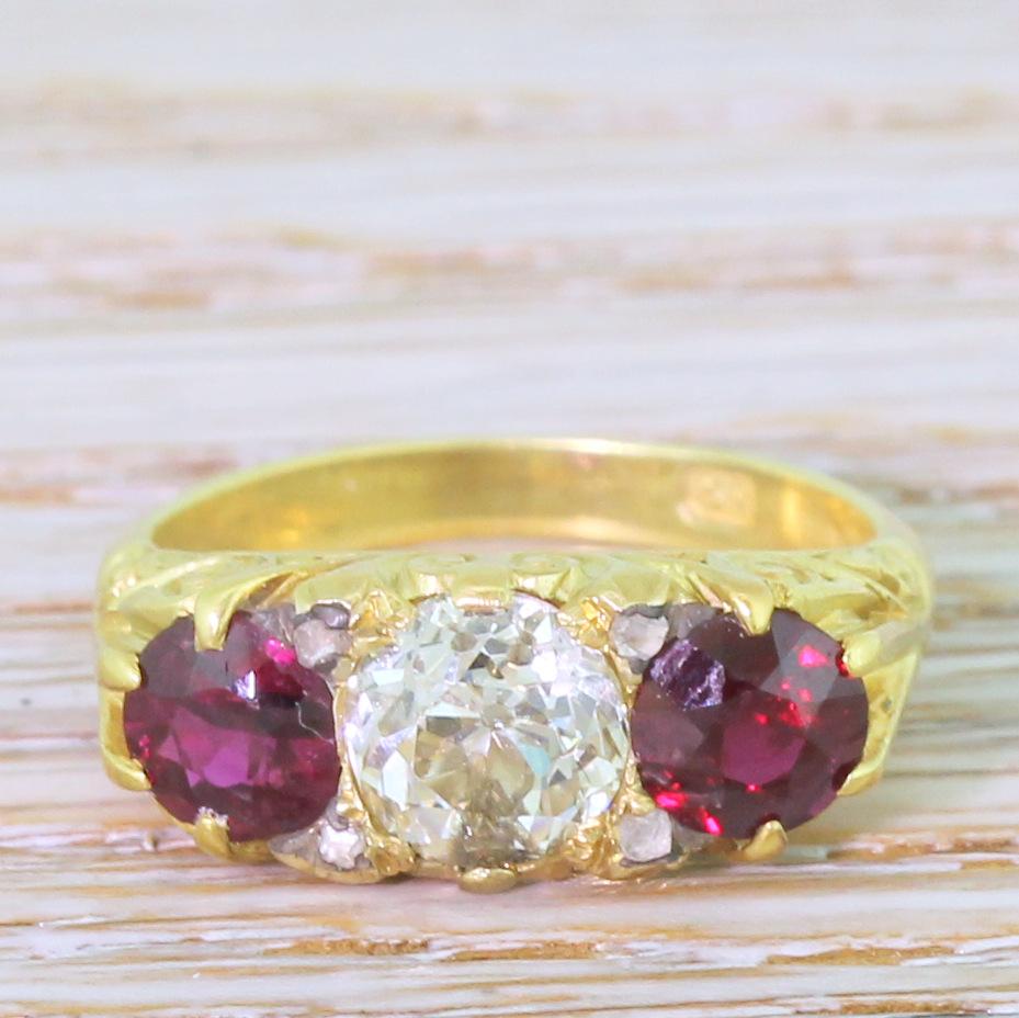 A delightful Victorian ruby and diamond ring. Centred by a 1.15 carat (approx.) old mine cut diamond, accented at each “corner” by four small rose cuts. A pair of rubies which display the perfect pigeon-blood red flank the centre stone within a