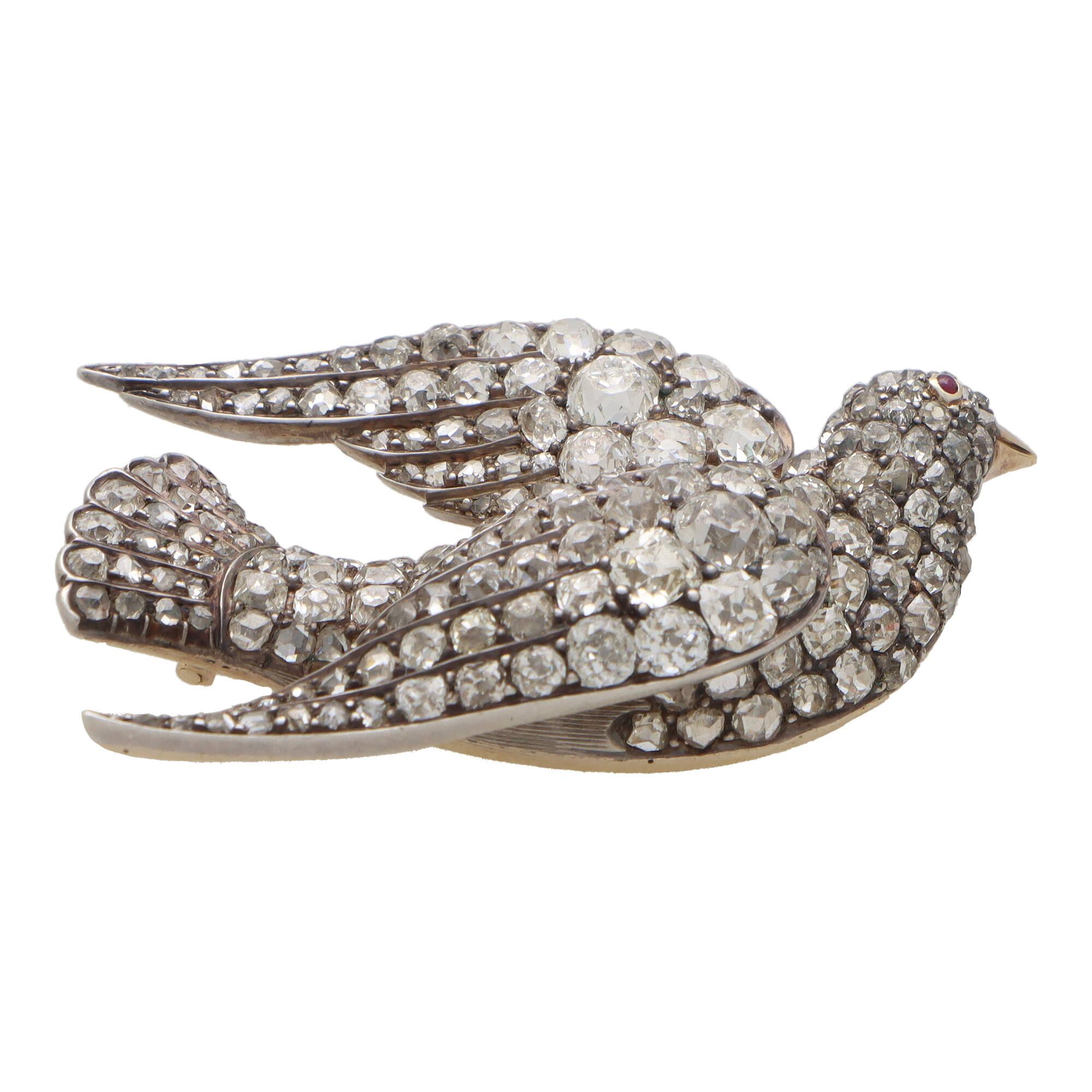 A beautiful Late Victorian old cut diamond bird brooch set in silver on gold.

The brooch depicts a flying bird set throughout with a mixture of rose cut, single cut and old cut diamonds. The piece has been cleverly crafted and designed so that each