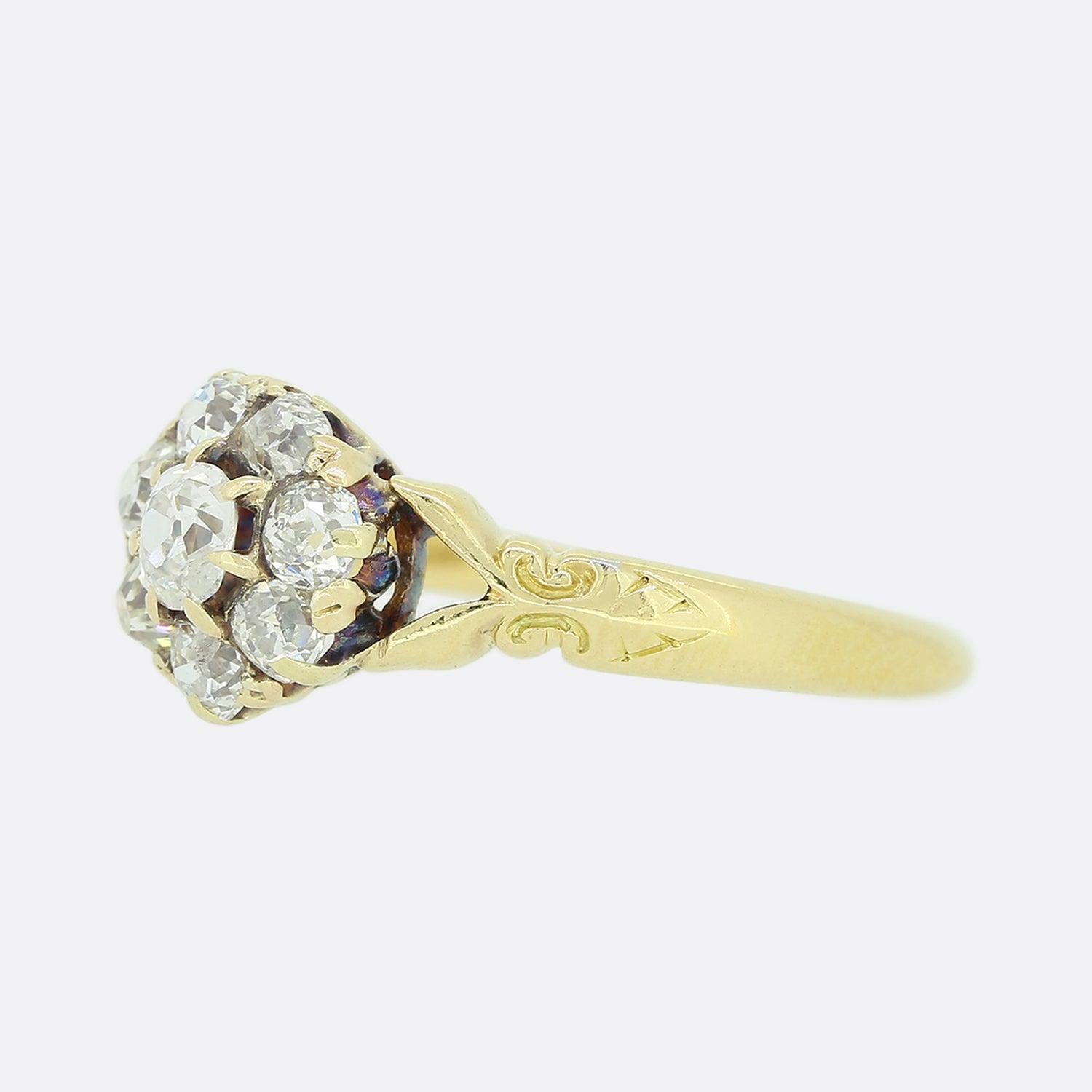 This is a victorian 18ct yellow gold diamond daisy ring. The ring plays host to a cluster of old cut diamonds that circulate a slightly larger oval shaped stone at the centre. Each diamond is claw set and sits between a pair of split open shoulders