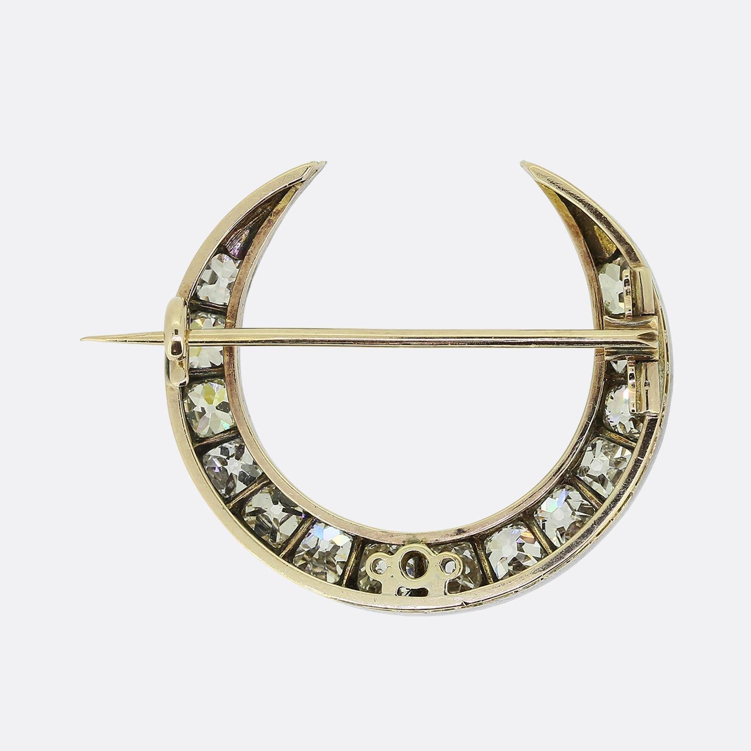Here we have a lovely moon crescent brooch dating back to the Victorian period. This curved frame has been crafted from yellow gold with a silver setting playing host to a single row of chunky round faceted old mine cut diamonds. These stones