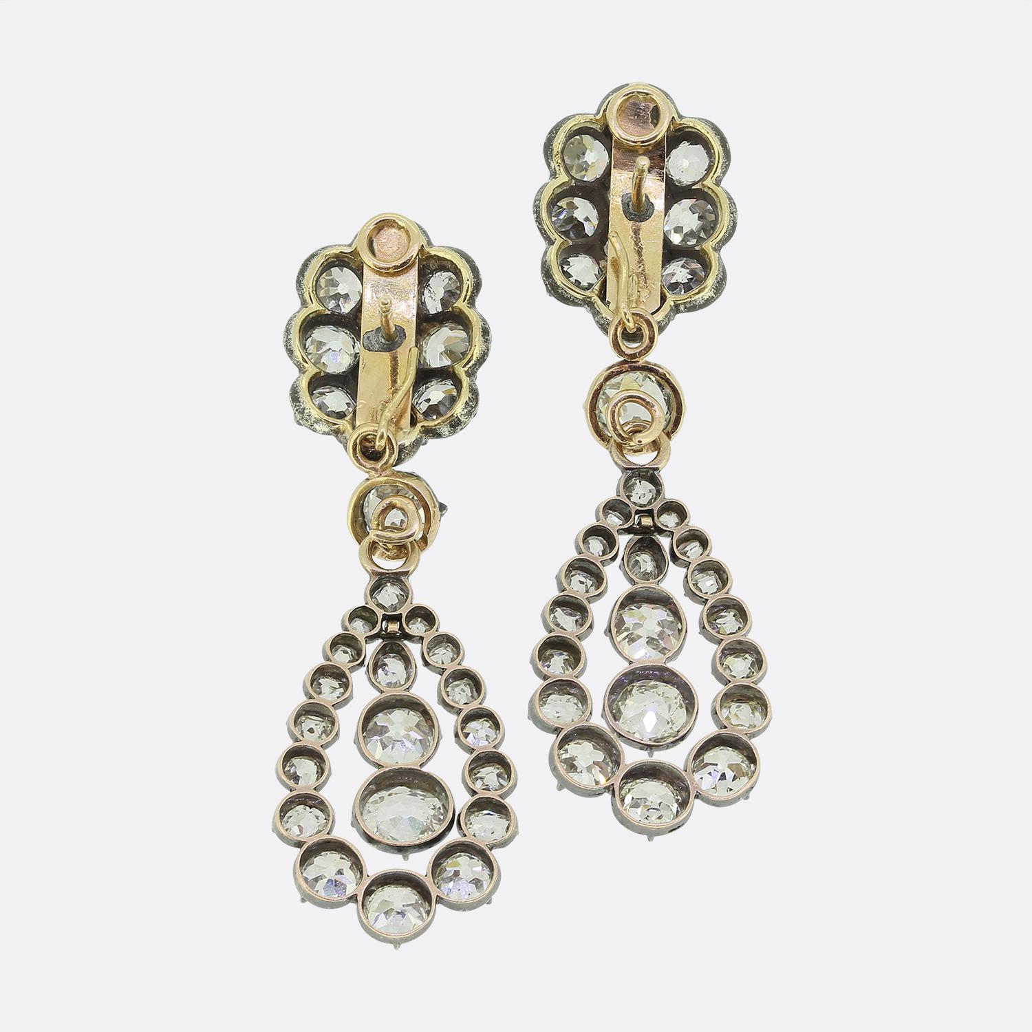 Here we have an exquisite pair of antique diamond drop earrings from the Victorian period. Each earring features an array of chunky old mine cut diamonds set in silver and backed in gold; a typical style of the era. The top clusters suspend a single