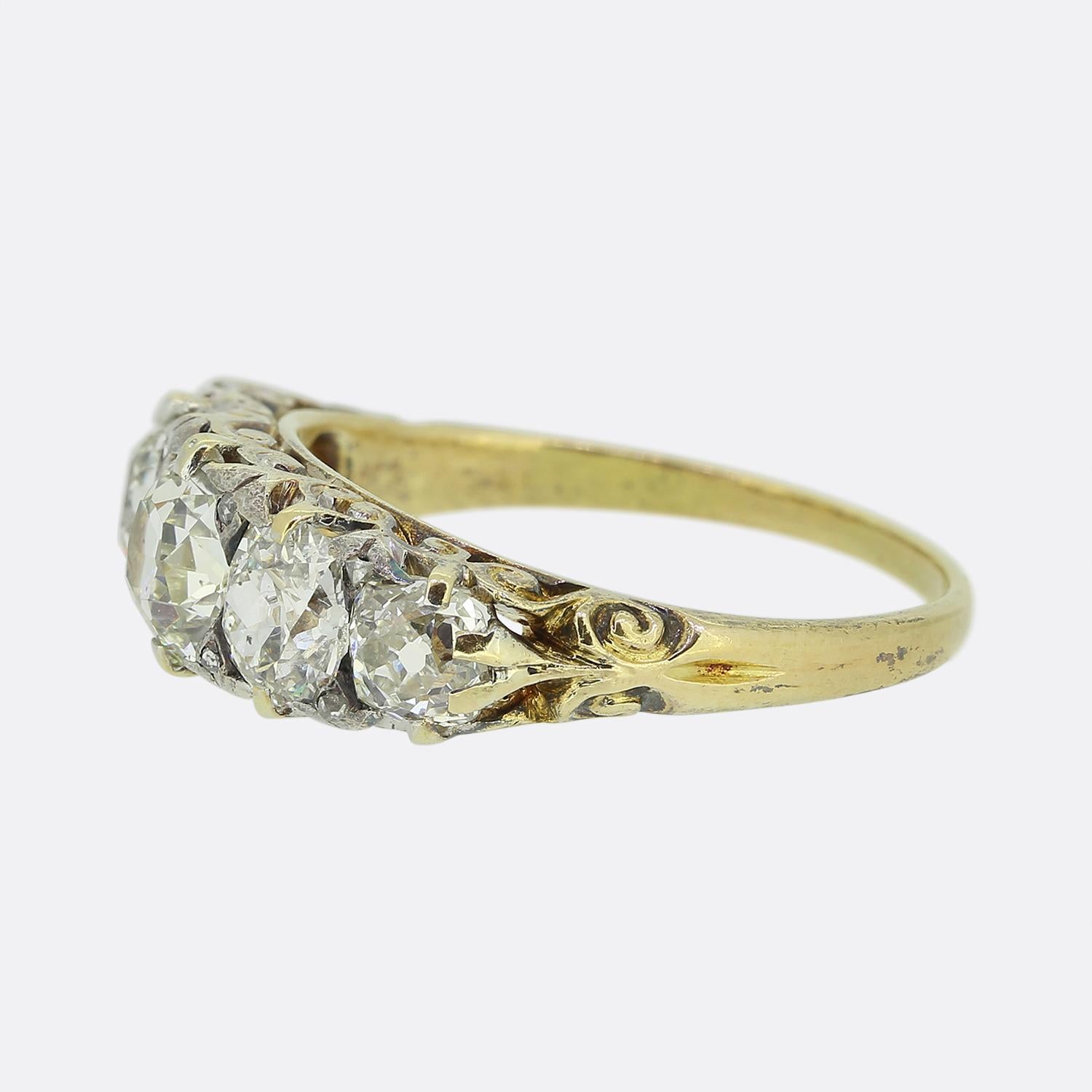 This is an 18ct yellow gold Victorian diamond five stone ring. The diamonds are bright white old cuts and feature a lovely sparkle. They also graduate in size with the largest in the centre. It is finished with elegant scroll work on the gallery in