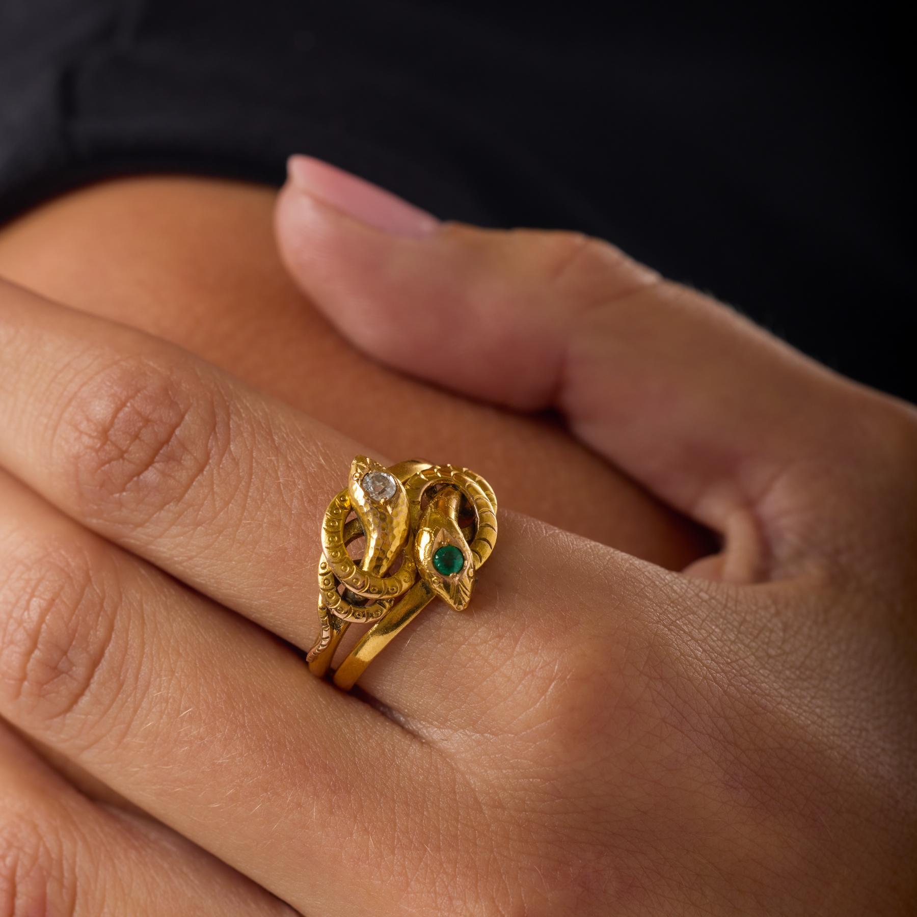 Cette bague serpent victorienne s'enroule gracieusement autour du doigt, sa forme expressive prenant vie grâce au doux éclat d'un diamant de taille européenne ancienne et à l'éclat vert vif d'une petite émeraude. La chaleur de l'or jaune 18 carats