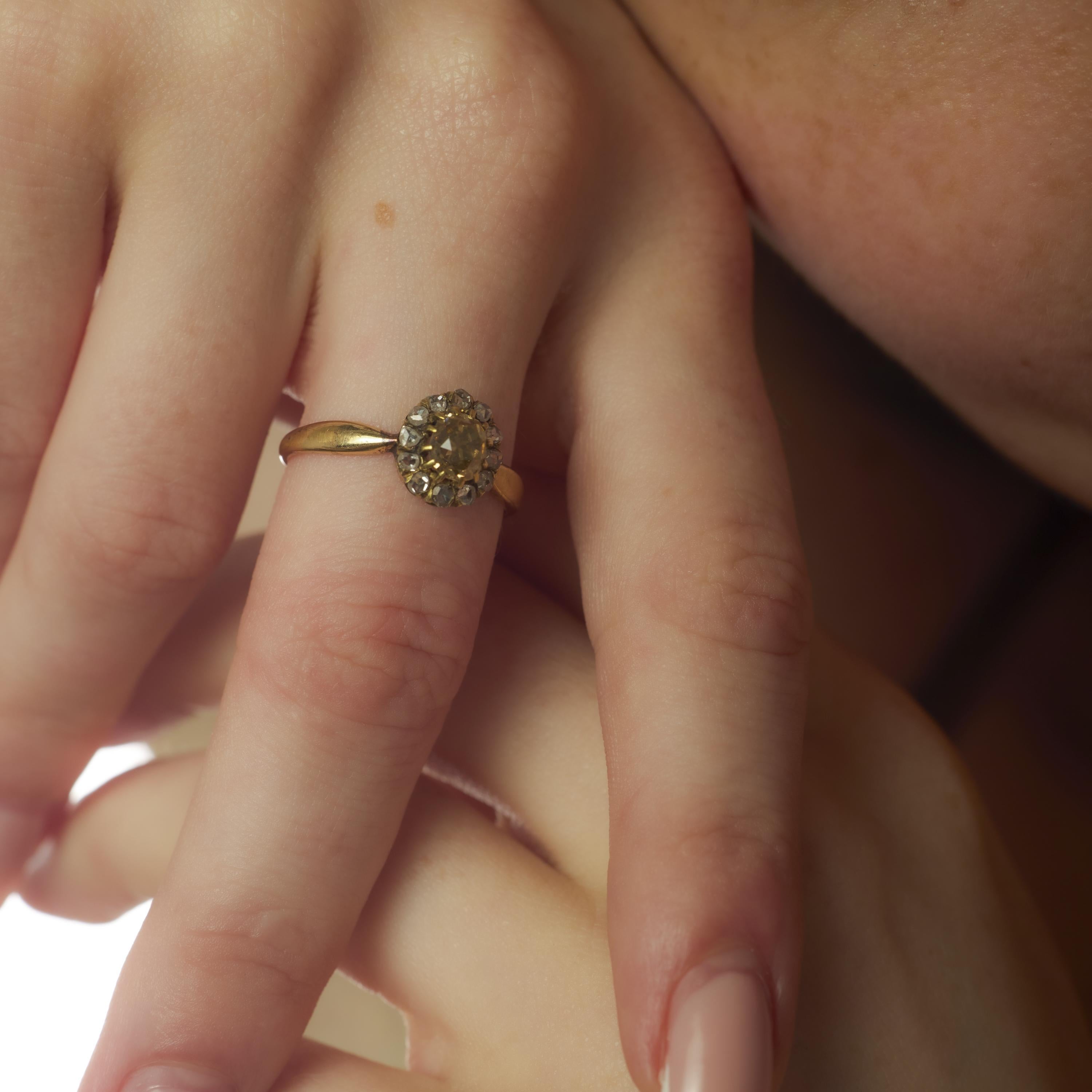 Cette bague victorienne antique respire la chaleur et l'élégance d'antan, autour d'un diamant taille ancienne de 0,75 carat de couleur brun fantaisie. Douze délicats diamants taillés en rose encerclent la pierre centrale, ajoutant un doux