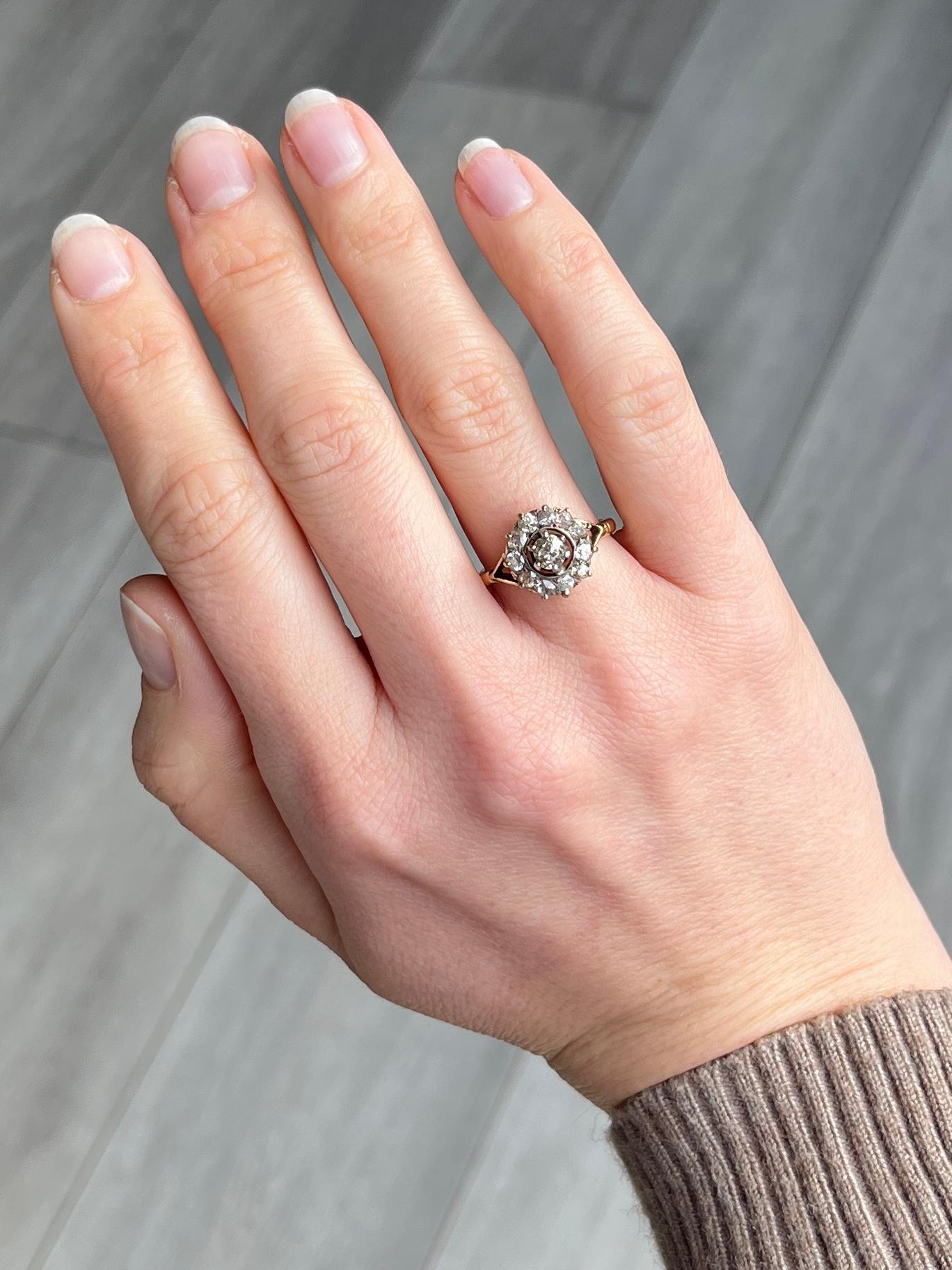 This stunning cluster ring holds old mine cut diamonds set within the platinum setting. The central stone measures approx 30pts and is surrounded by a halo of smaller old mine cut diamonds. The head is sat on a simple 18carat gold band with split