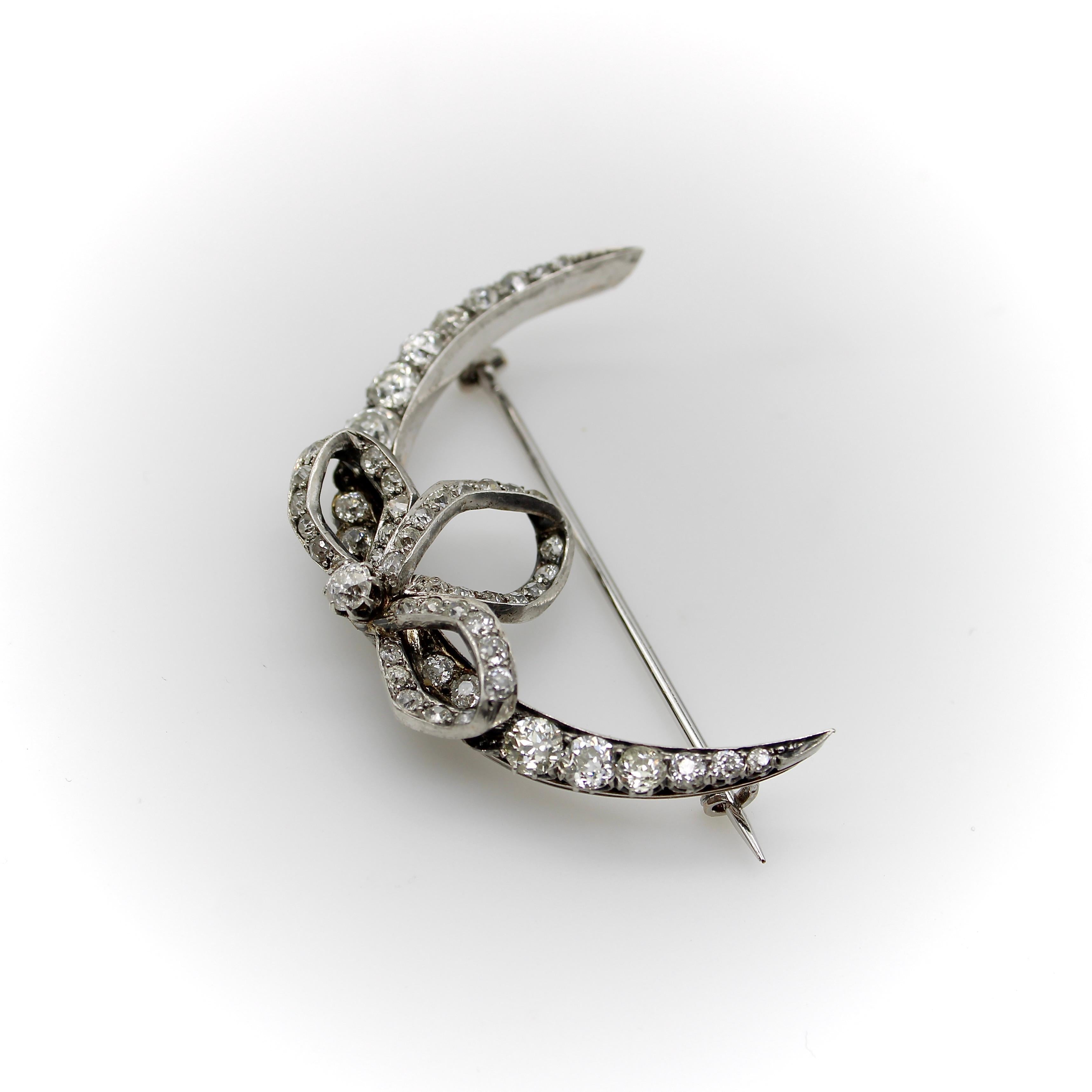 This enchanting brooch is shaped like a crescent moon adorned with a romantic bow. It is silver topped and gold backed, encrusted with 56 stunning Old Mine Cut diamonds. The brooch embodies everything we love about celestial jewelry, capturing the