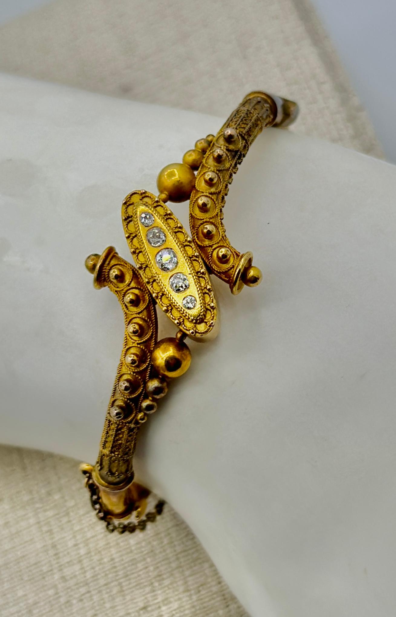 THIS IS A STUNNING ANTIQUE VICTORIAN ETRUSCAN REVIVAL 14-18 KARAT GOLD AND OLD MINE CUT DIAMOND BANGLE BRACELET.
The hinged bangle bracelet has museum quality Etruscan hand applied bead and rope work accents of extraordinary detail.  In the center