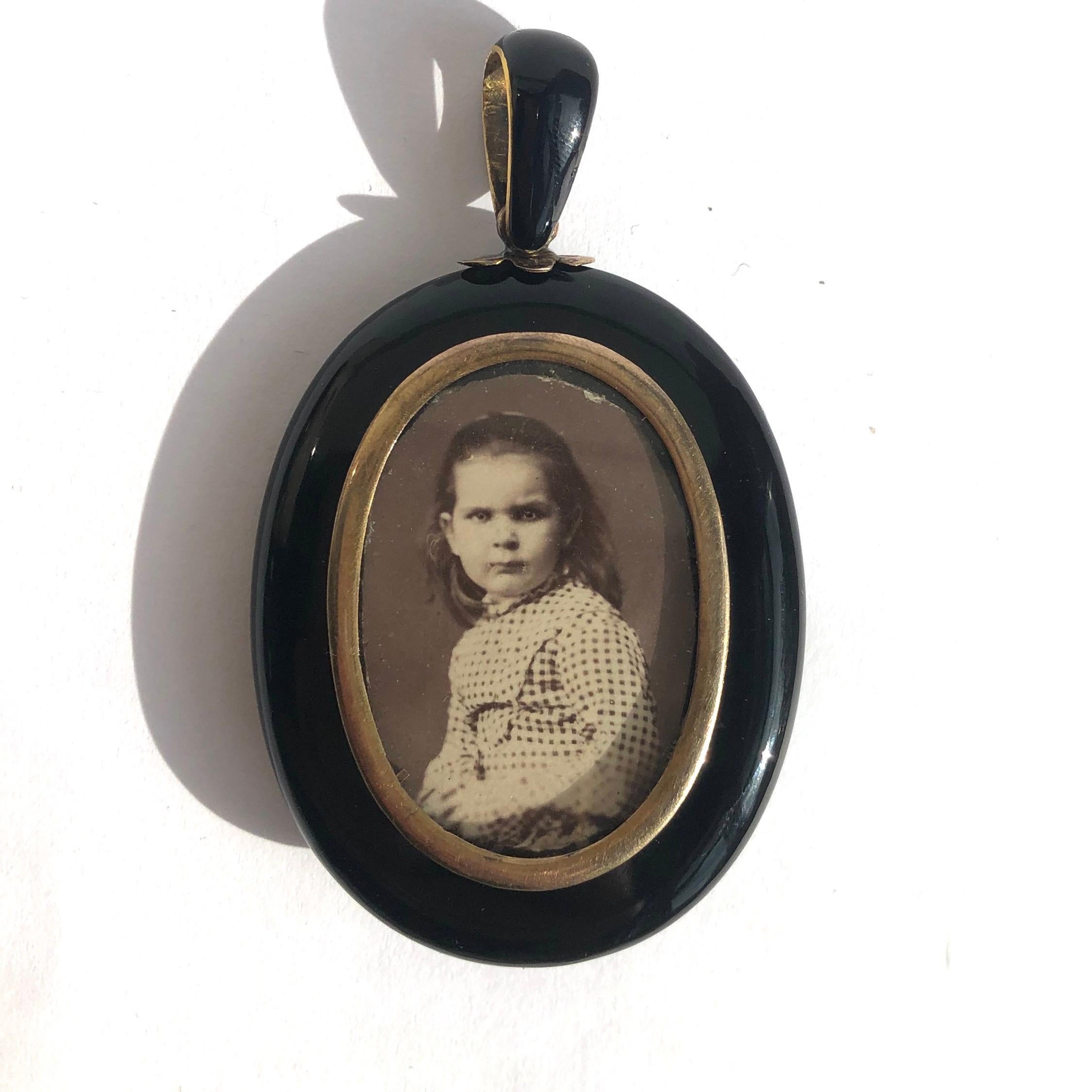 The size of this locket makes this piece a real show stopper. The glossy black Onyx with the gold central star encrusted with pearls is fabulous! In the glazed panel on the back of this locket is a picture of a sweet little girl in a gold frame.