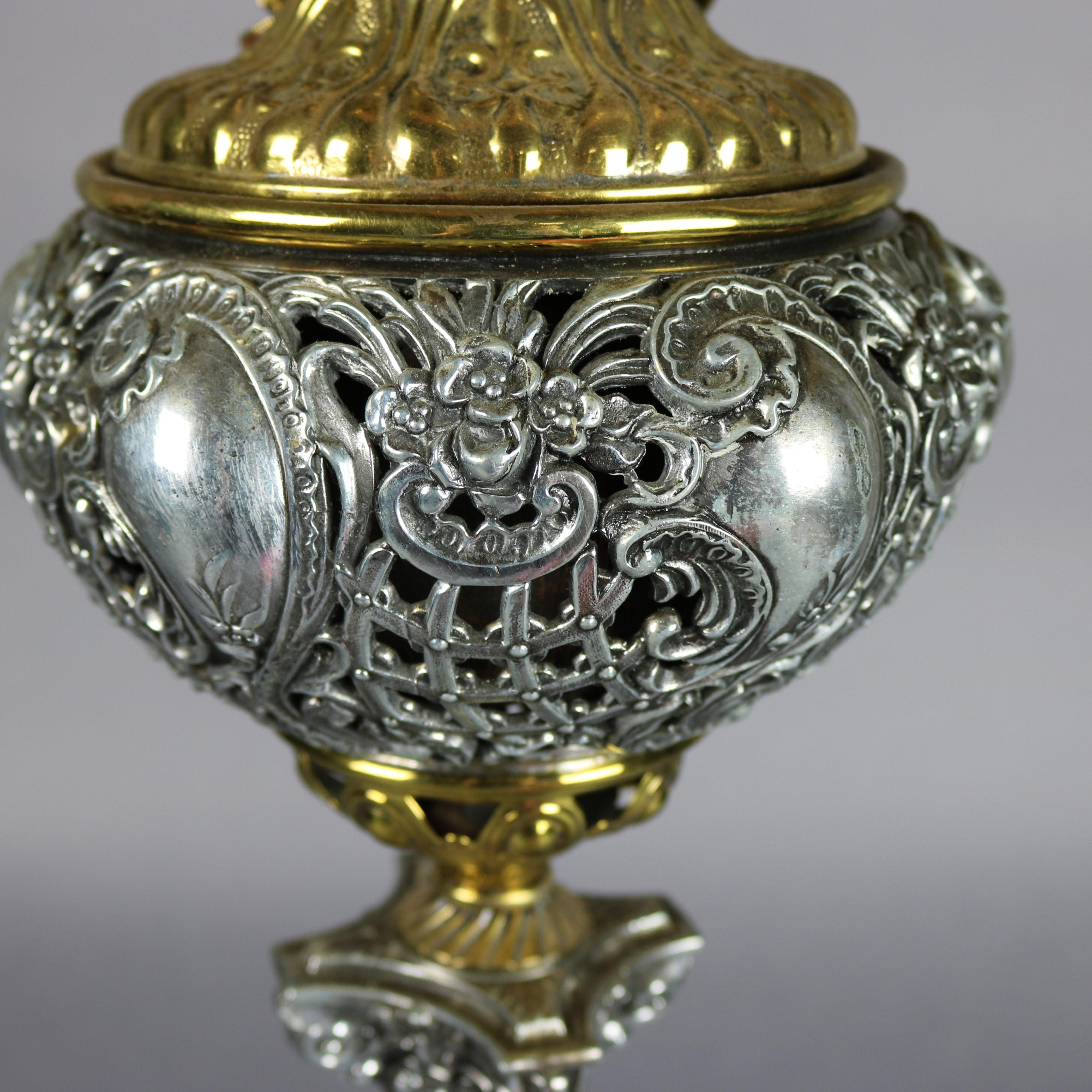 A Victorian electrified parlor lamp offers hand painted floral globe with peonies surmounting onyx & gilt metal base in Corinthian column-form with pierced scroll and foliate font and seated on footed plinth with scroll, foliate and mask relief