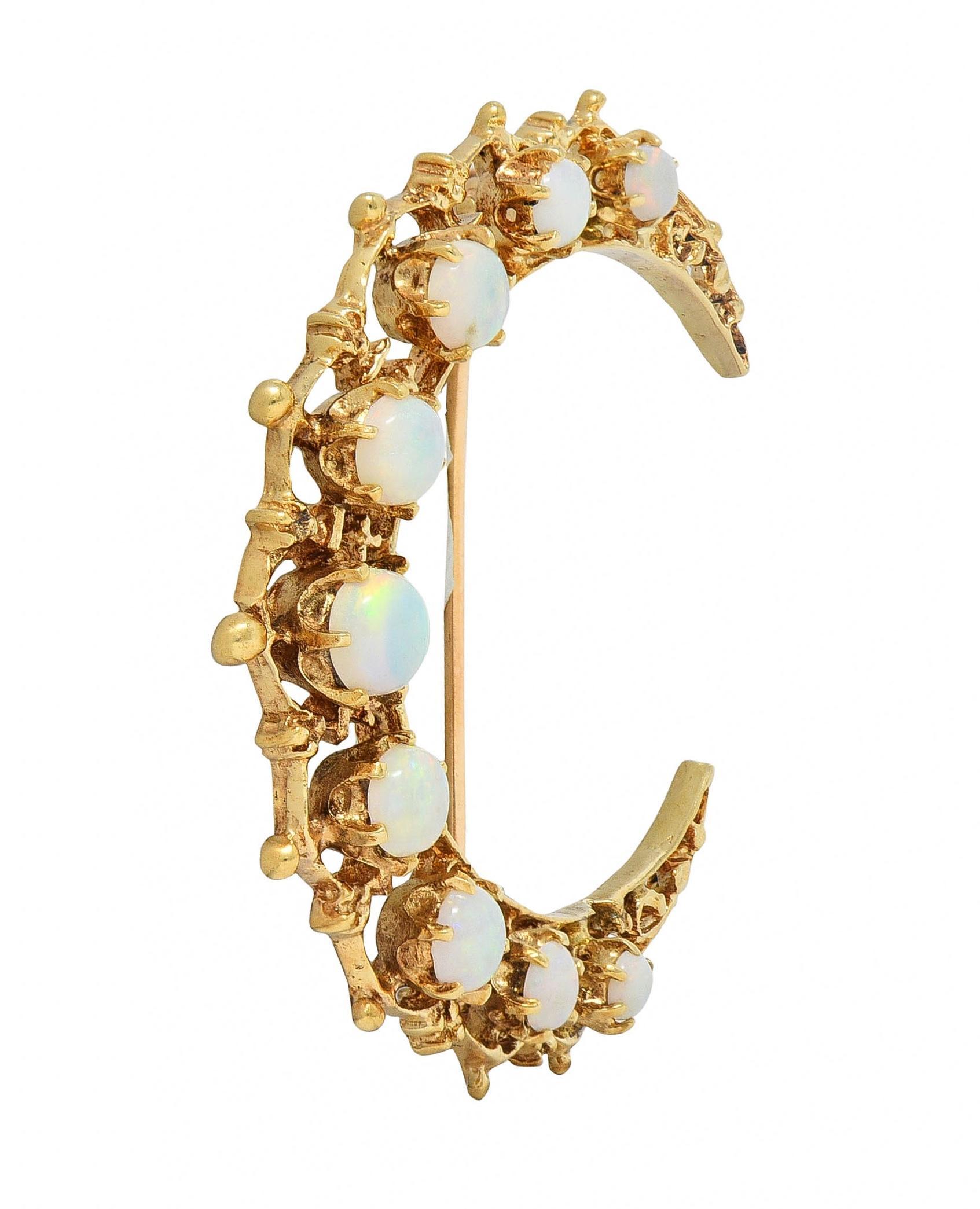 Designed as an ornately pierced scroll motif crescent-shaped form 
Featuring round-shaped opal cabochons prong set throughout
Translucent white in body color with spectral play-of-color
Graduated and ranging in size from 2.7 mm to 4.5 mm
Completed