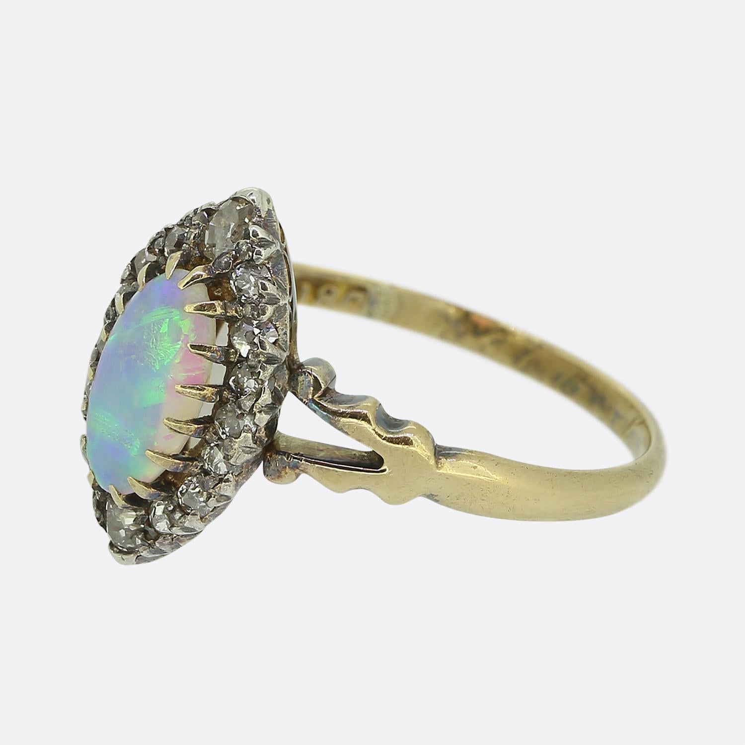Here we have an elegant navette ring taken from the Victorian era. At the centre of the face we find an oval shaped white opal, displaying a strong blue hue with subtle flashes of oranges and greens. Surrounding the opal is a frame of round faceted