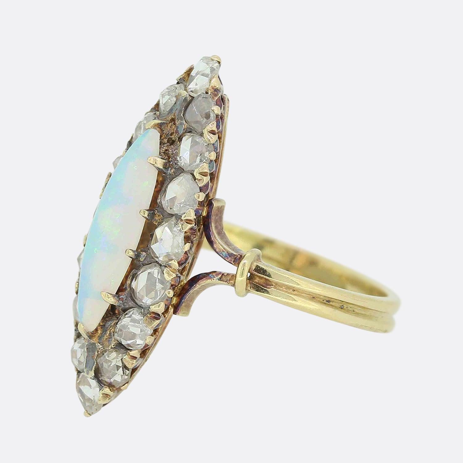Here we have an opal and diamond navette ring from the Victorian era. This antique piece showcases an endearing oval shaped opal with a deep play of colour which sits well proportioned at the centre of the face. This focal gemstone is accentuated by