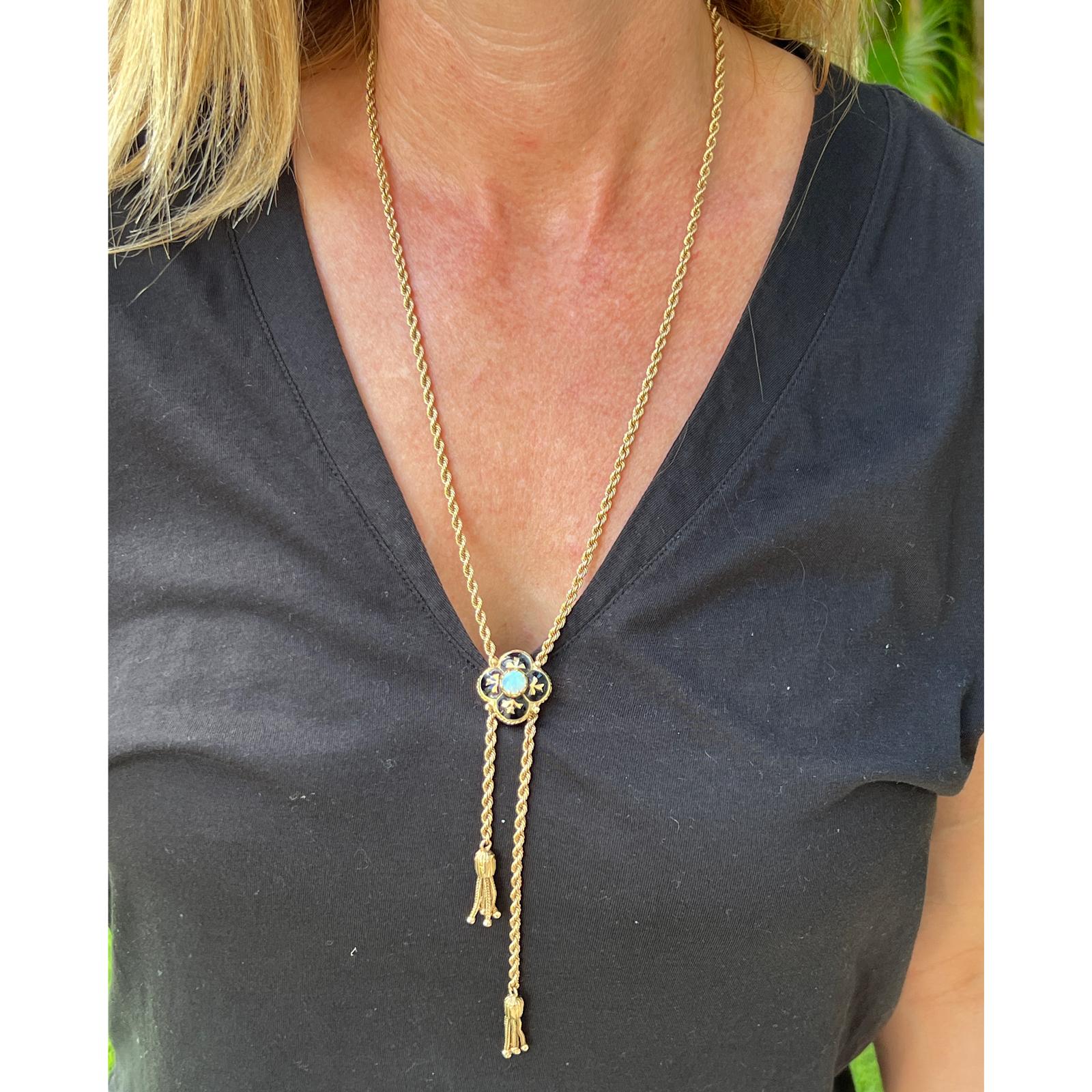 Victorian antique slide necklace fashioned in 14 karat yellow gold. The necklace features an opal and black enamel clover shape slide, rope chain measuring 26 inches, and tassel ends. The enamel is in excellent condition.  Weight: 10.4 grams. 