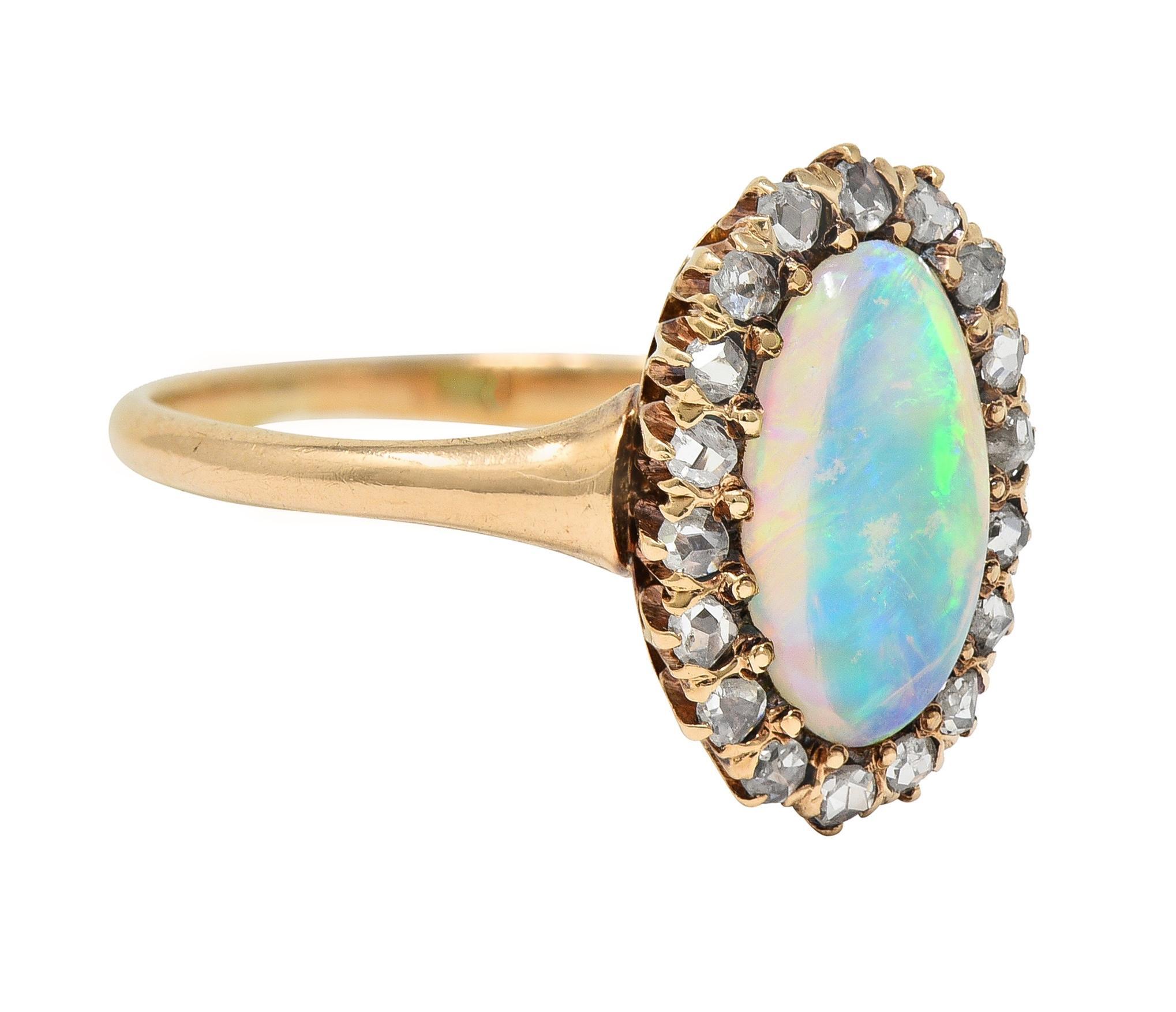 Centering an oval-shaped opal cabochon measuring 6.0 x 10.5 mm 
Translucent white in body color with strong spectral play-of-color 
Bead set with a halo surround of rose cut diamonds 
Weighing approximately 0.18 carat total 
Eye clean and bright -
