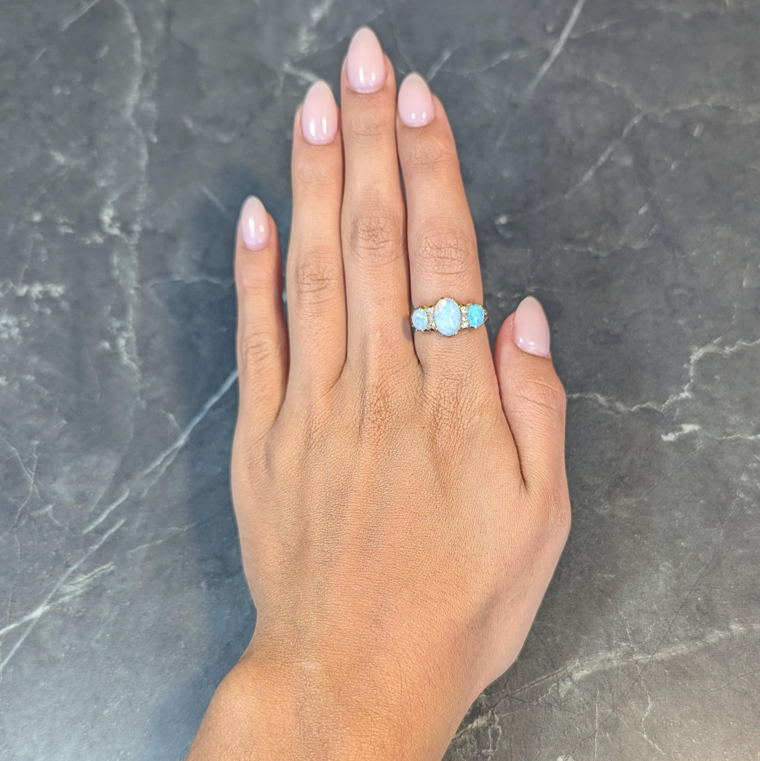 Featuring three oval-shaped opal cabochons prong set east to west
Graduated and ranging in size from 4.5 x 5.5 mm to 7.0 x 10.0 mm 
Translucent white in body color with spectral play-of-color
Accented by old single cut diamonds bead set in