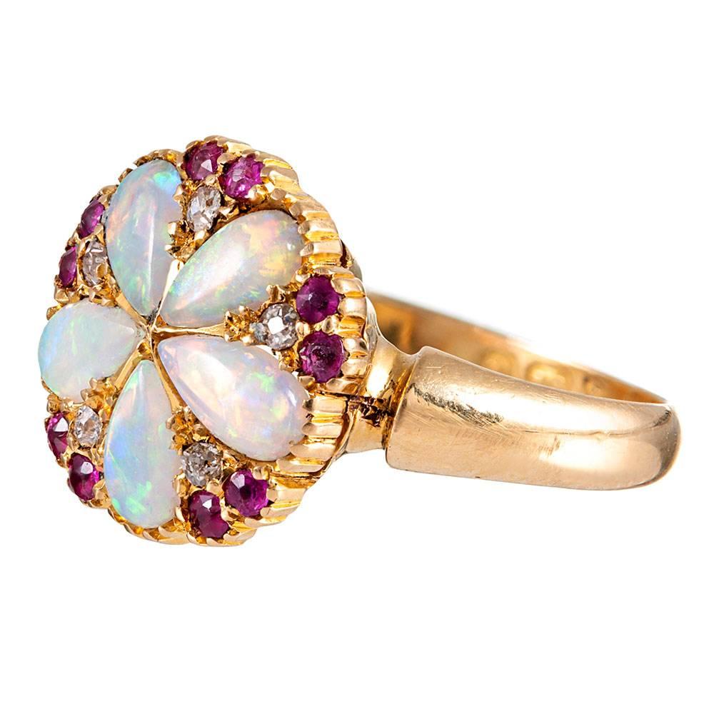 Sweet and feminine, the ring’s design is centered upon five pear-shaped “petals” of opal, with red rubies and white diamonds peppered symmetrically between. The color combination is delicious! This style easily lends itself to daily wear, as the