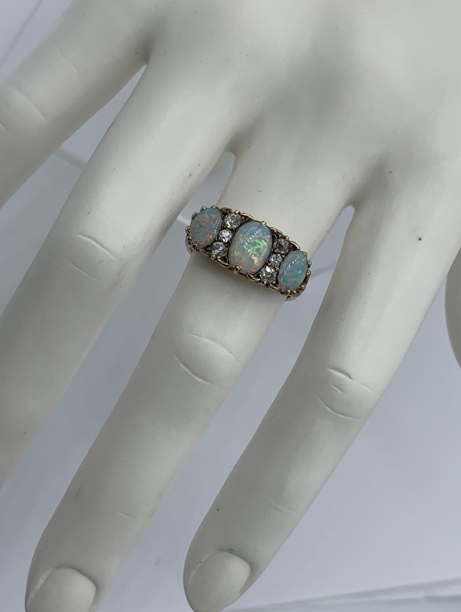This is an Antique Victorian - Edwardian Ring with three gorgeous natural oval Opals of incredible color and stunning beauty. The three Opal gems are accented by six sparkling antique Old Mine Cut Diamonds.   The jewels are set in a scroll motif