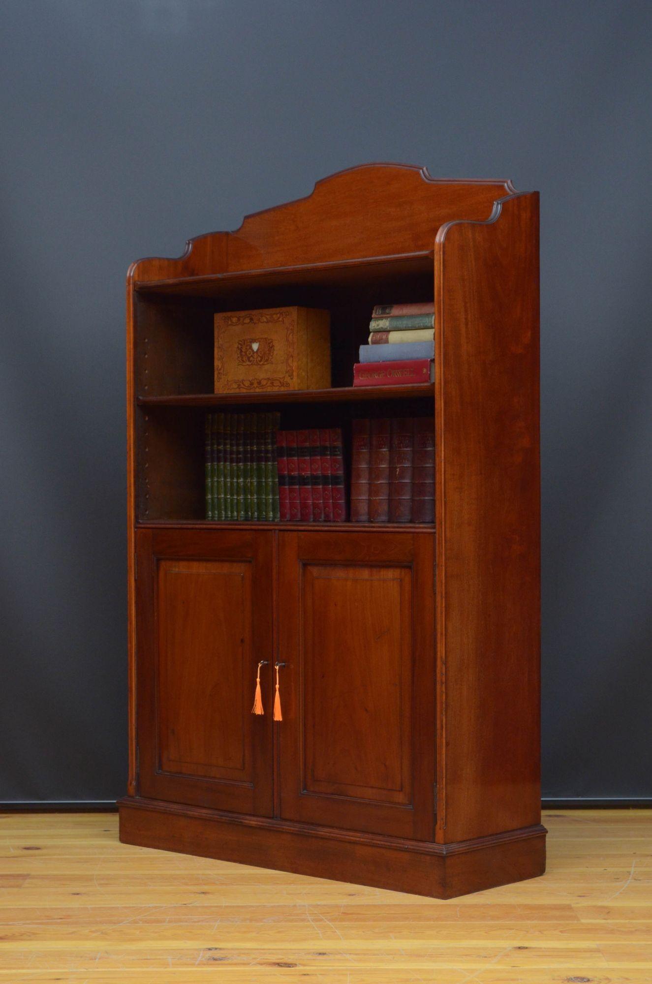 St036 A Victorian solid mahogany open bookcase, having shaped gallery to the top with moulded edge and height adjustable shelf above a pair of panelled cupboard door fitted with working locks and two keys and enclosing height adjustable shelves, all