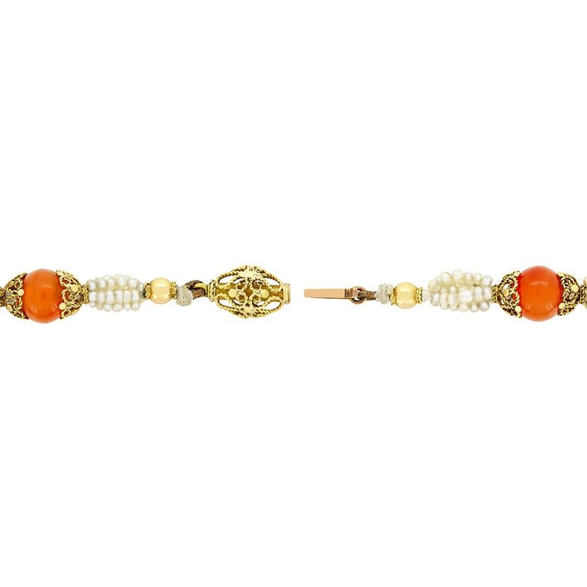 Un'affascinante collana vittoriana con una classica combinazione di perle e calcedonio. Ci sono in totale 18 calcedoni arancioni che completano i grappoli di piccole perle naturali d'acqua salata. Le perle variano di dimensione, partendo da 1,5 mm