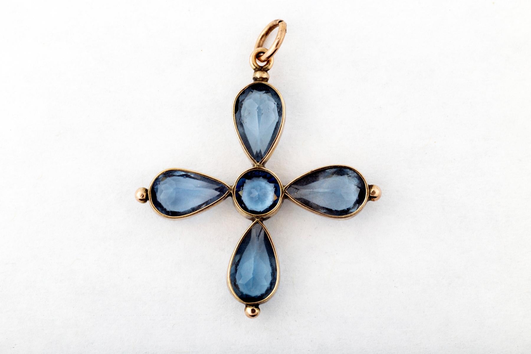 A Victorian Blue paste cross set in 15 kt gold and made in England c. 1870. The various colors of antique paste can be breathtaking. The setting of these stones is open backed allowing al light to celebrate the cornflower blue color. Brilliant blue