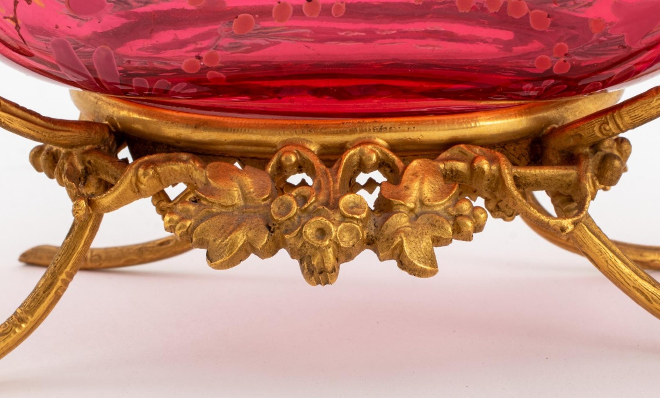 Victorian ormolu and enameled rose pink glass toilet set, circa 1900, and comprising a shaped rectangular mirror supported by two flanking caryatids above a tray en gondole with two scent flacon perfume bottles, and a ring tray on vine-wreathed