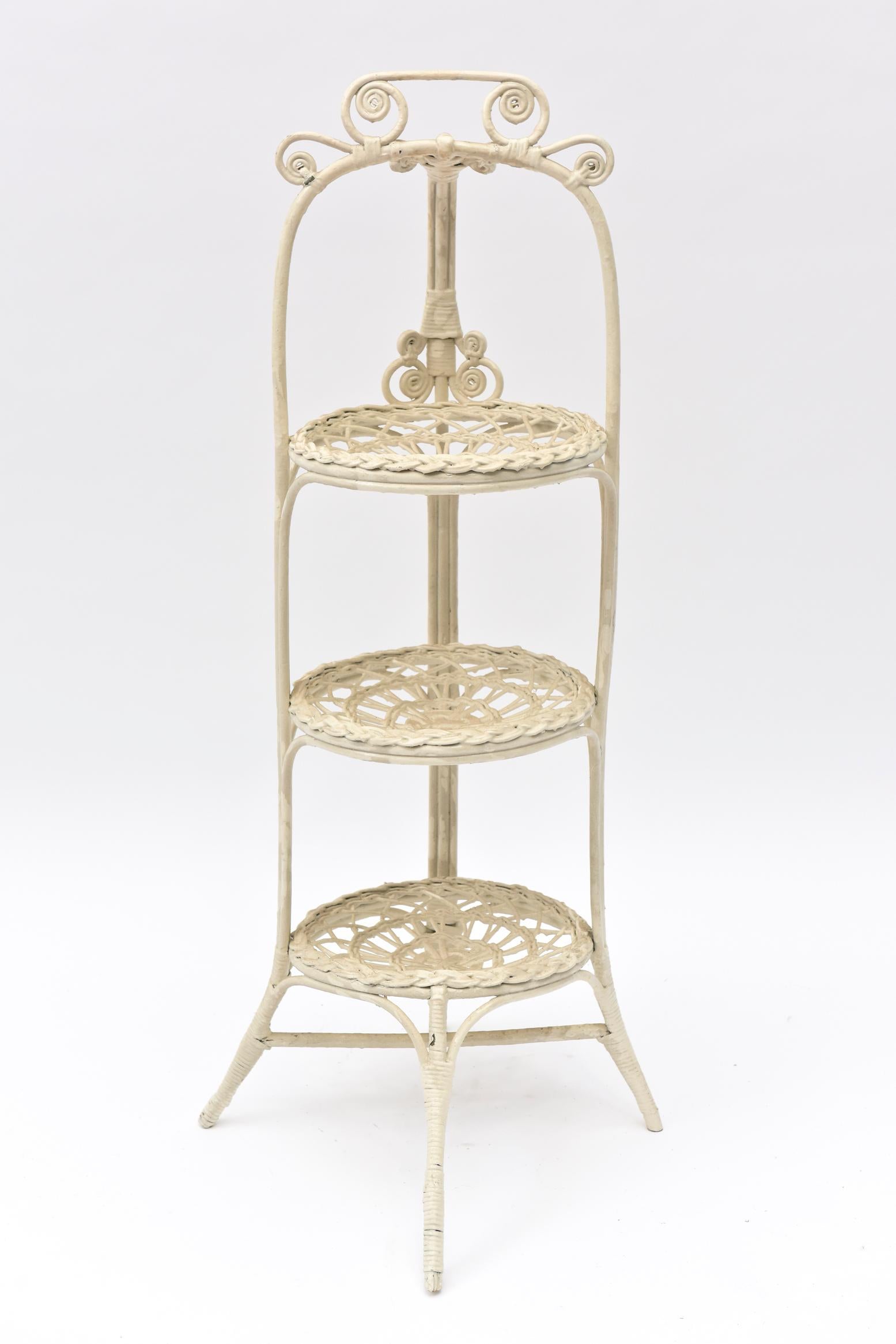 The ornate muffin stand has splay feet and 3 tiers made to hold 3 cake or muffin plates. The base and top of the handle have ornate curlicues while the plate holder sections are intricately woven to show off the round area where plates of sweets