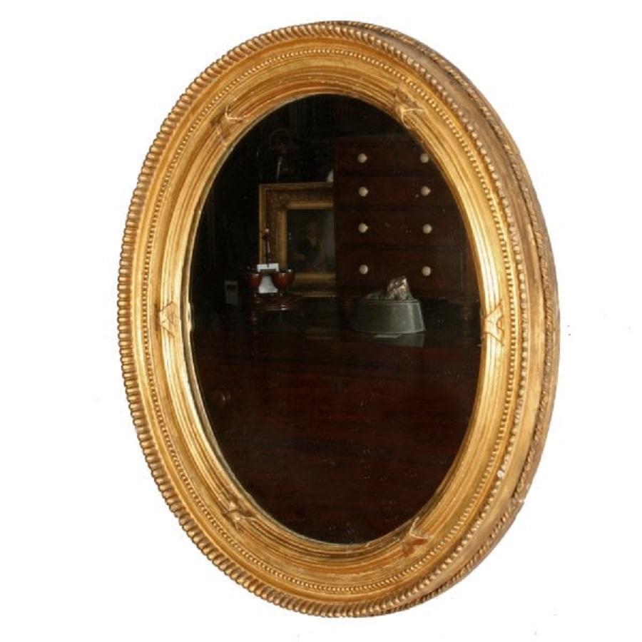 A mid 19th century Victorian oval carved wood and gesso gilt wall mirror.

The frame has a gadrooned outer edge with an inner reeded band that has cross over ribbons and in-between a band of 'Pea' decoration.

The frame is original with some