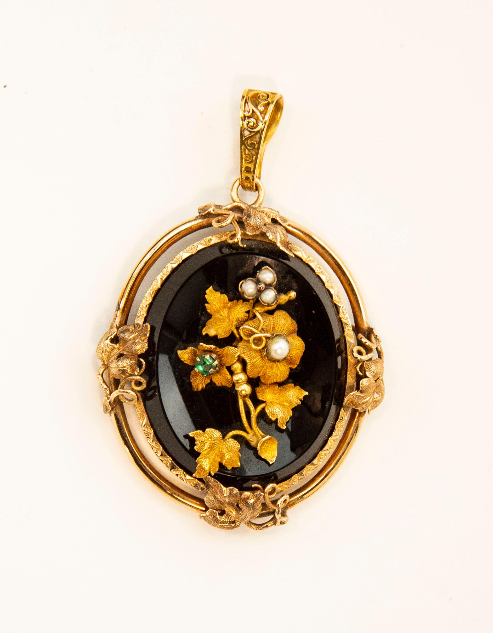 A Victorian antique 14 karat oval onyx pendant with a floral decoration assembled of pearls, emerald, and engraved gold leaves with petals. The pendant is dating back to the early 20th century, and it belonged to the mourning jewelry. In the past,