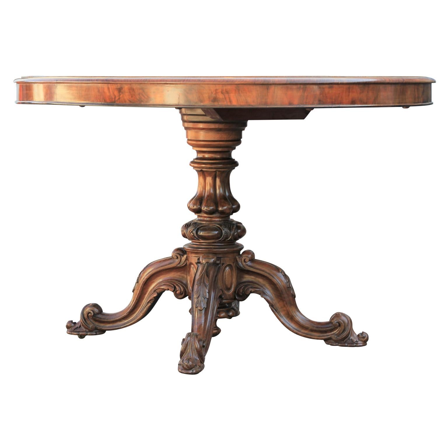 A late 19th century oval center table with beautiful quarter veneered burr walnut tilt-top accented with satinwood inlaid details on each corner. The top is supported by a sturdy base with four curved legs. This piece is in great antique condition
