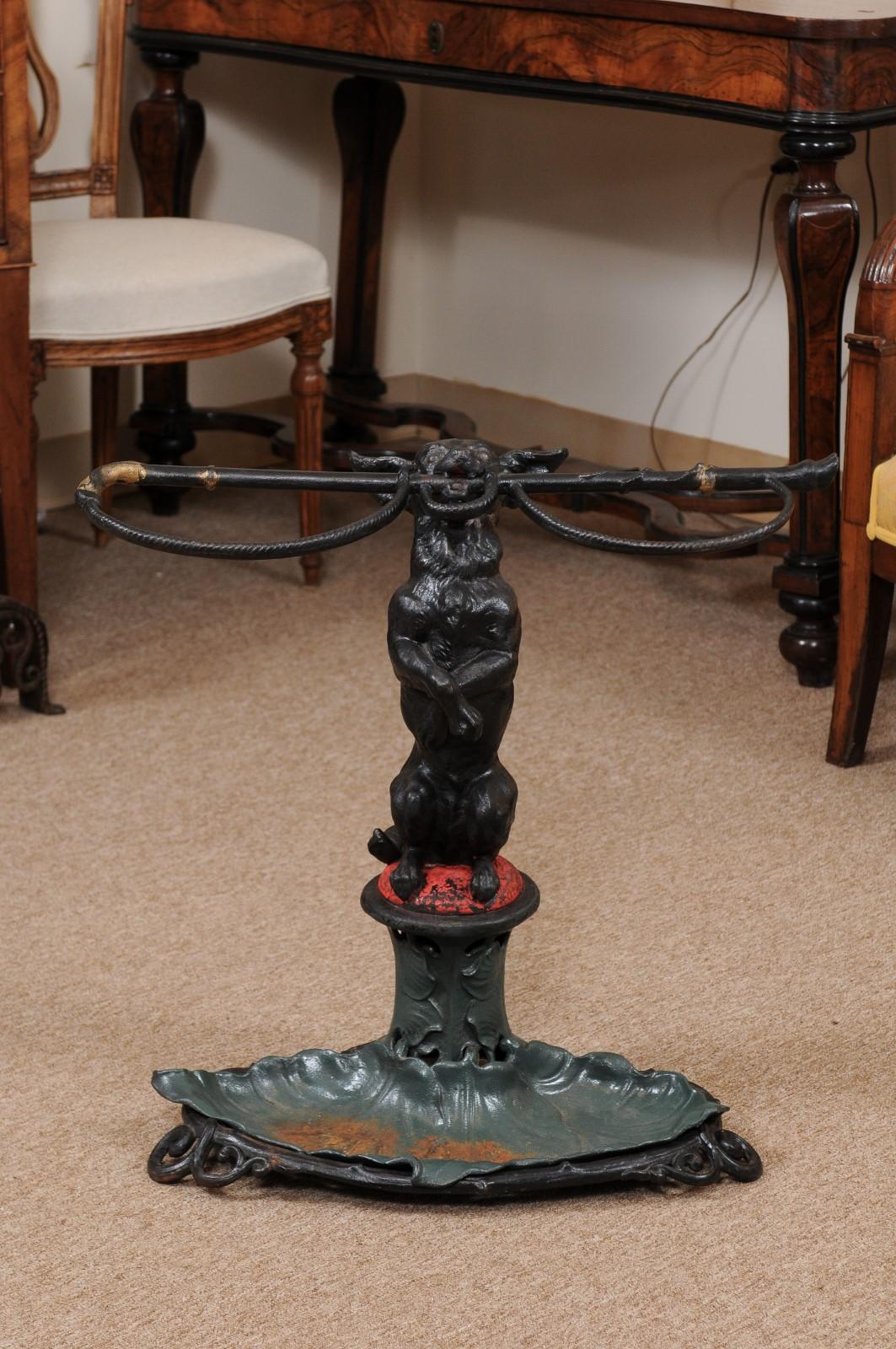 A Victorian painted iron umbrella stand with dog holding a riding crop in his mouth and leaf from drip basin. The stand stamped 