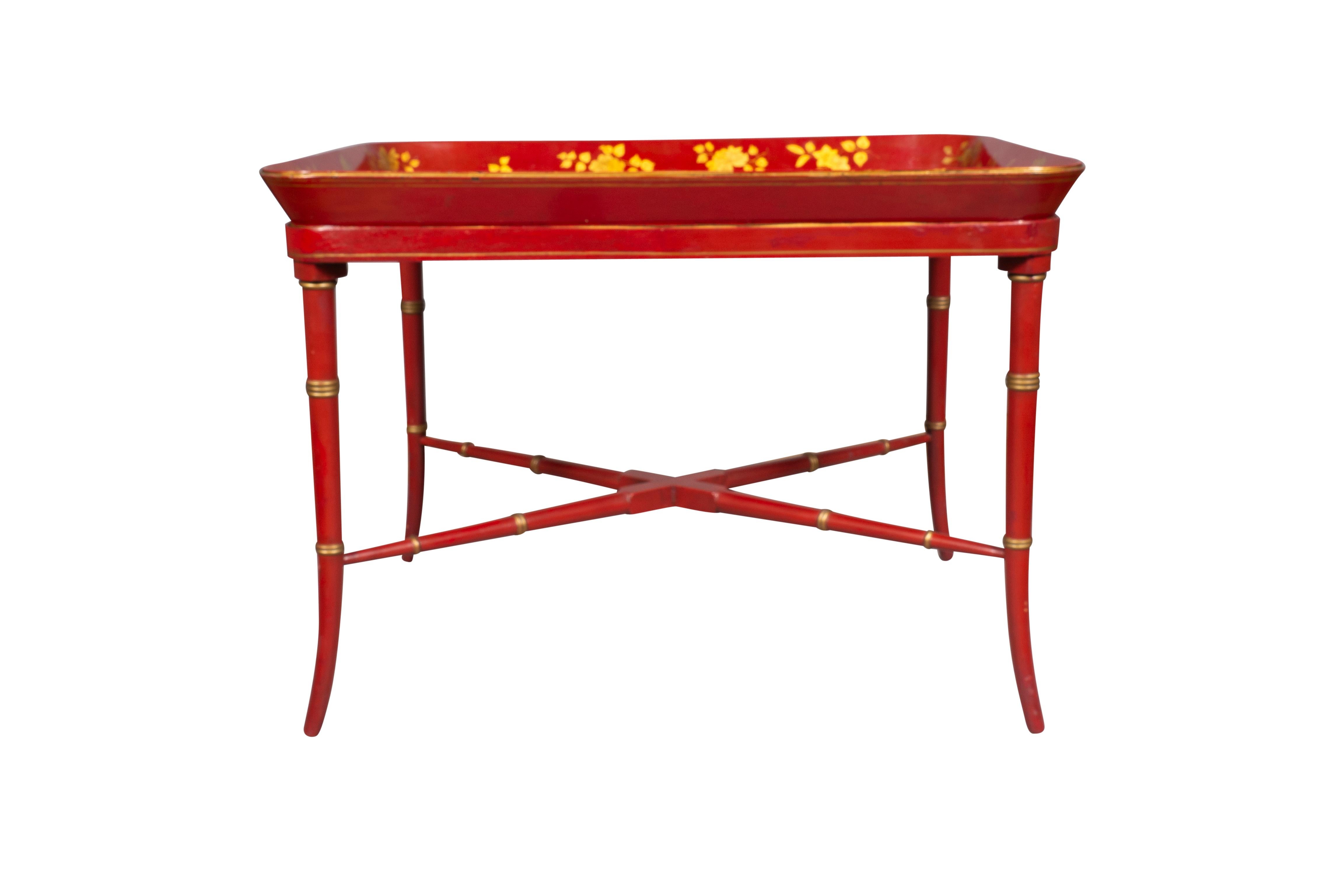 Rectangular with a brilliant red ground with leaves and flowers and butterflies in gilt. The base with faux bamboo legs and stretcher. Ex- Hyde Park Antiques NYC.