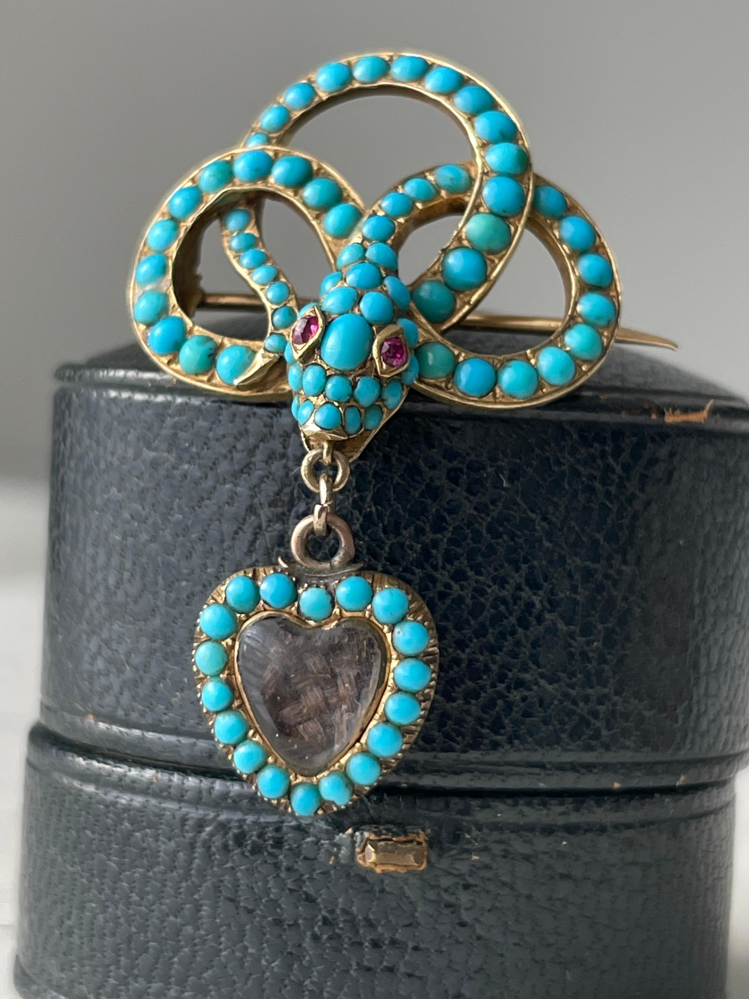 The serpent was a Victorian era symbol of everlasting love and devotion. Rendered in 15k gold, the body of this delightful coiled snake is pave-set with bright turquoise cabochons and accented with glowing ruby eyes. A tiny heart shaped charm