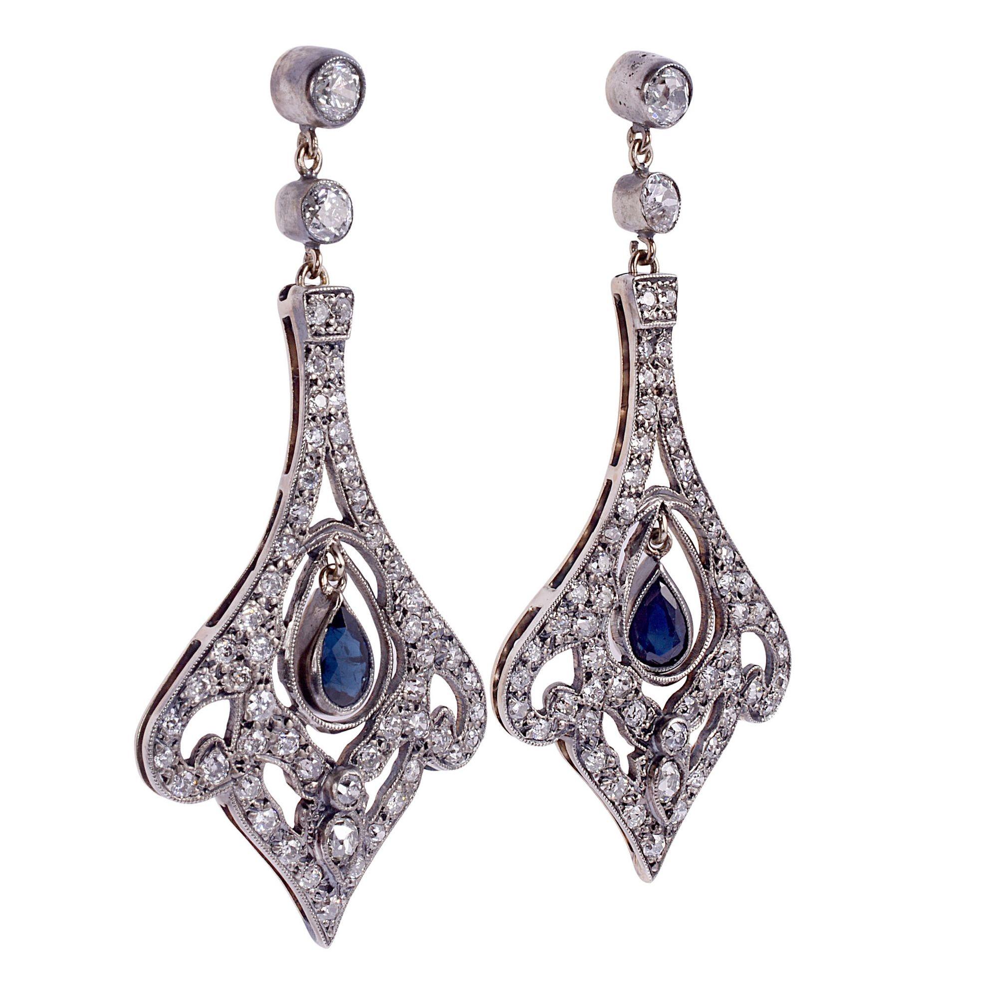 Victorian pear sapphire & diamond dangle earrings, circa 1900. The Victorian dangle earrings are crafted in 14K gold topped with silver. They feature a pear sapphire drop in the center of a pave diamond earring with milgrain detailing. The sapphires