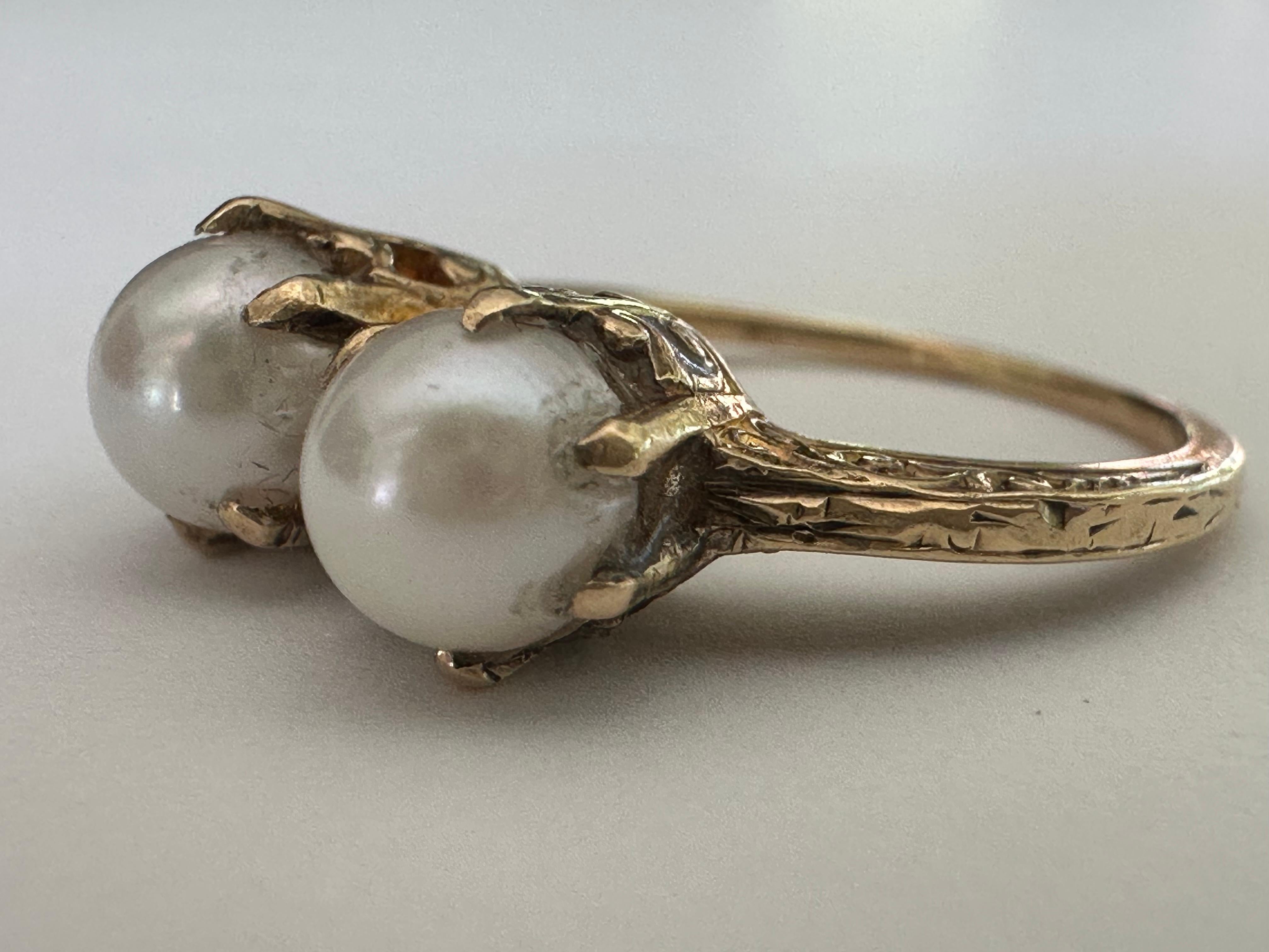 Ein wunderschönes Paar glänzender weißer Perlen schimmert aus dem Inneren dieses viktorianischen Toi-et-Moi-Rings in einer aufwändig handgravierten Fassung aus 14-karätigem Gelbgold. Die Perlen messen etwa 5,5-6 mm. CIRCA Ende des zwanzigsten
