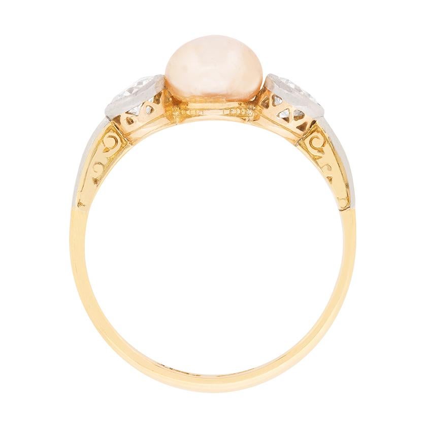 This unique ring dates back to the 1900s, the Victorian era. In the middle is a wonderful natural pearl with a stunning pink hue. It measure 6.6mm and has been expertly glued into it's setting. Either side are rub over set old cut diamonds which