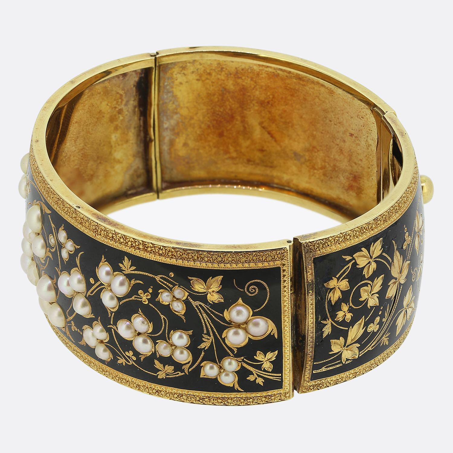 Hier haben wir einen wunderschönen übergroßen Armreif aus der viktorianischen Zeit. Dieses antike Stück wurde aus 18-karätigem Gelbgold gefertigt und zeichnet sich durch verschlungene florale Muster aus, die mit natürlich schimmernden weißen Perlen