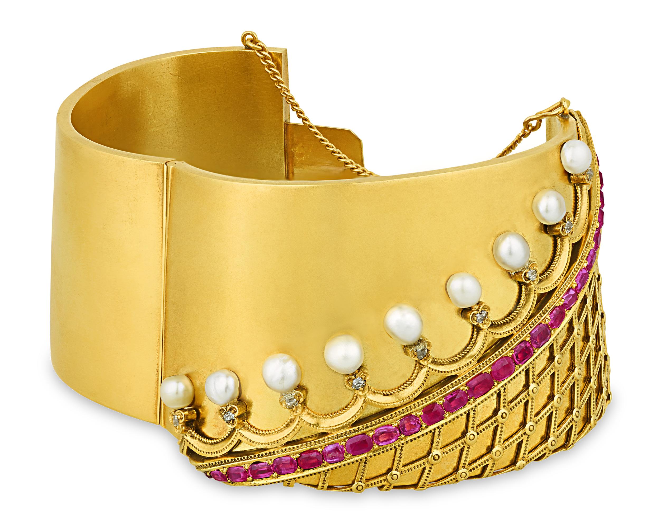 This pearl and ruby cuff bracelet epitomizes classic refinement. The 14K Gold bracelet resembles the embroidered cuff of a Victorian-era gown, complete with a trim elevated by lustrous natural pearls and sparkling diamonds. The cross-hatching