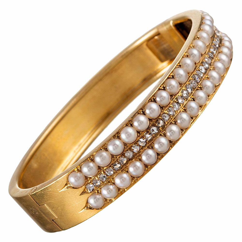 A classically styled Victorian bangle rendered in 18 karat yellow gold and set with a single row of rose cut diamonds, flanked by a row of lustrous white pearls. This would make a sweet addition to the collection of any antique enthusiast, is