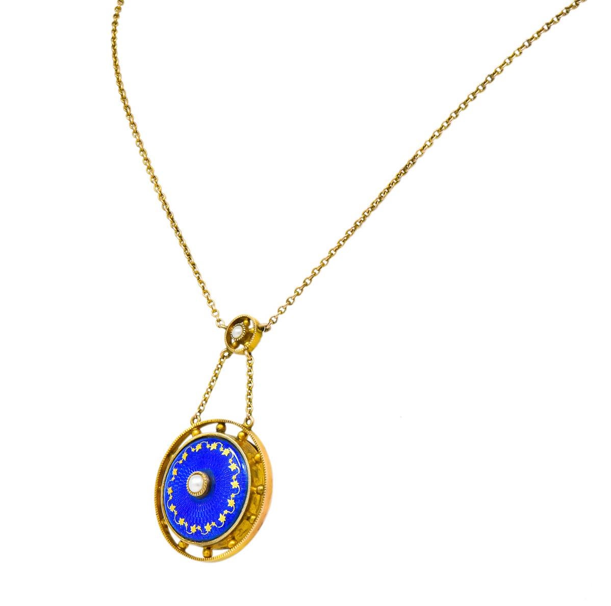 Centering a small, bezel set, round, natural freshwater pearl surrounded by radiating royal blue enamel, with no loss, and a gold ivy motif

Surrounded by inner and outer round gold millegrain frames accented with gold beads

Suspended by cable