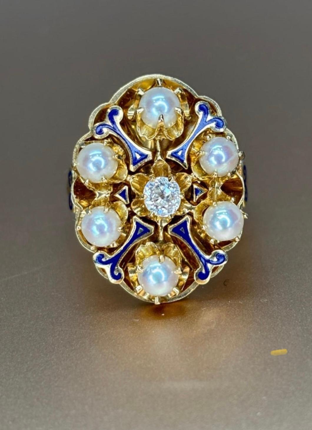 This fabulous oval shaped ring dating from the late 1800s, features a central bright-white .20ct. antique old European cut diamond sparkling amidst an interlacing design of bright glossy cobalt blue enamel and a halo of luminous white pearls.