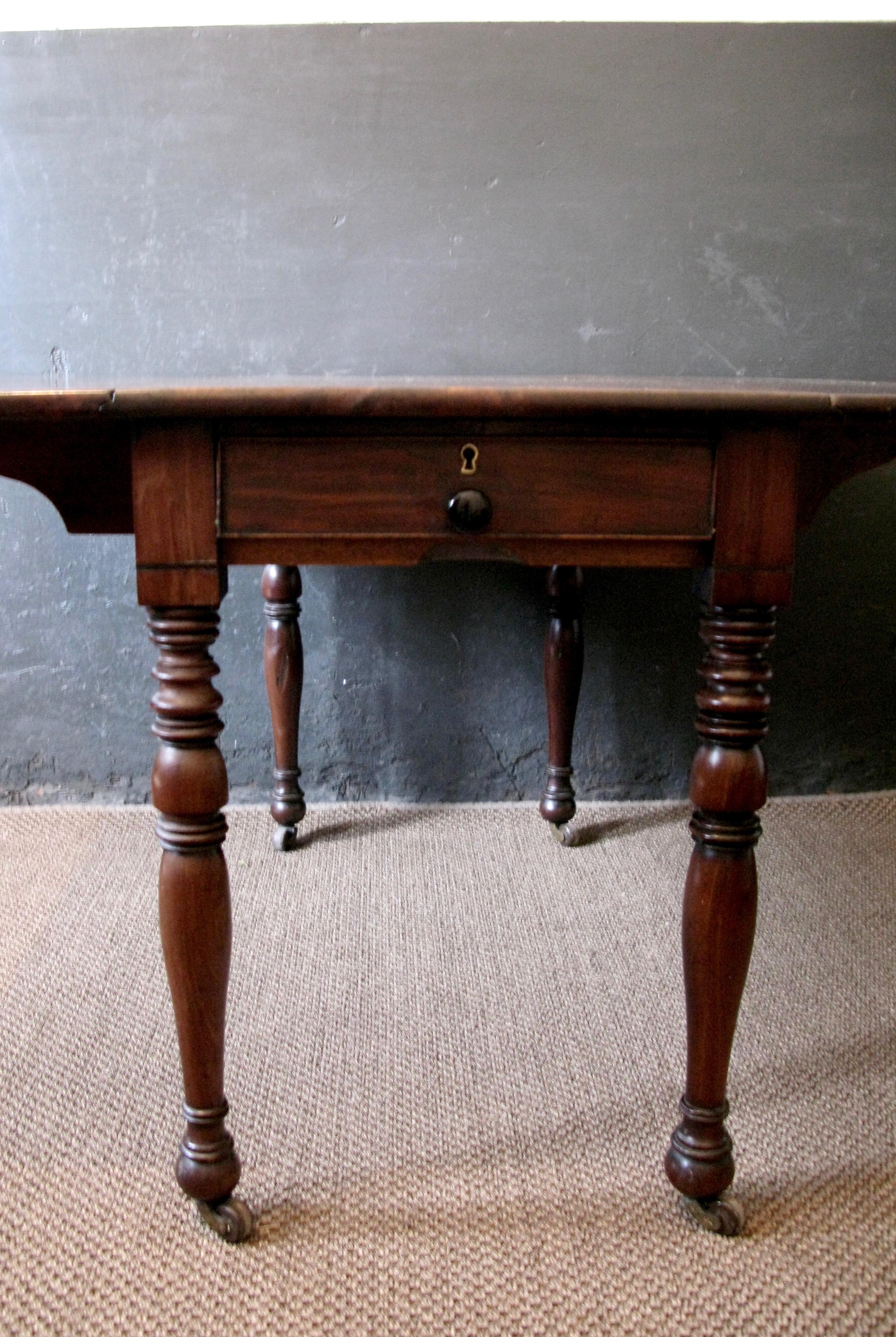 This is a lovely antique victorian pembroke large table.
 An English, early Victorian, flame mahogany, drop-flap side table dating to the early 19th century, having a lovely figured solid mahogany top with drop leafs, a single lined drawer at one