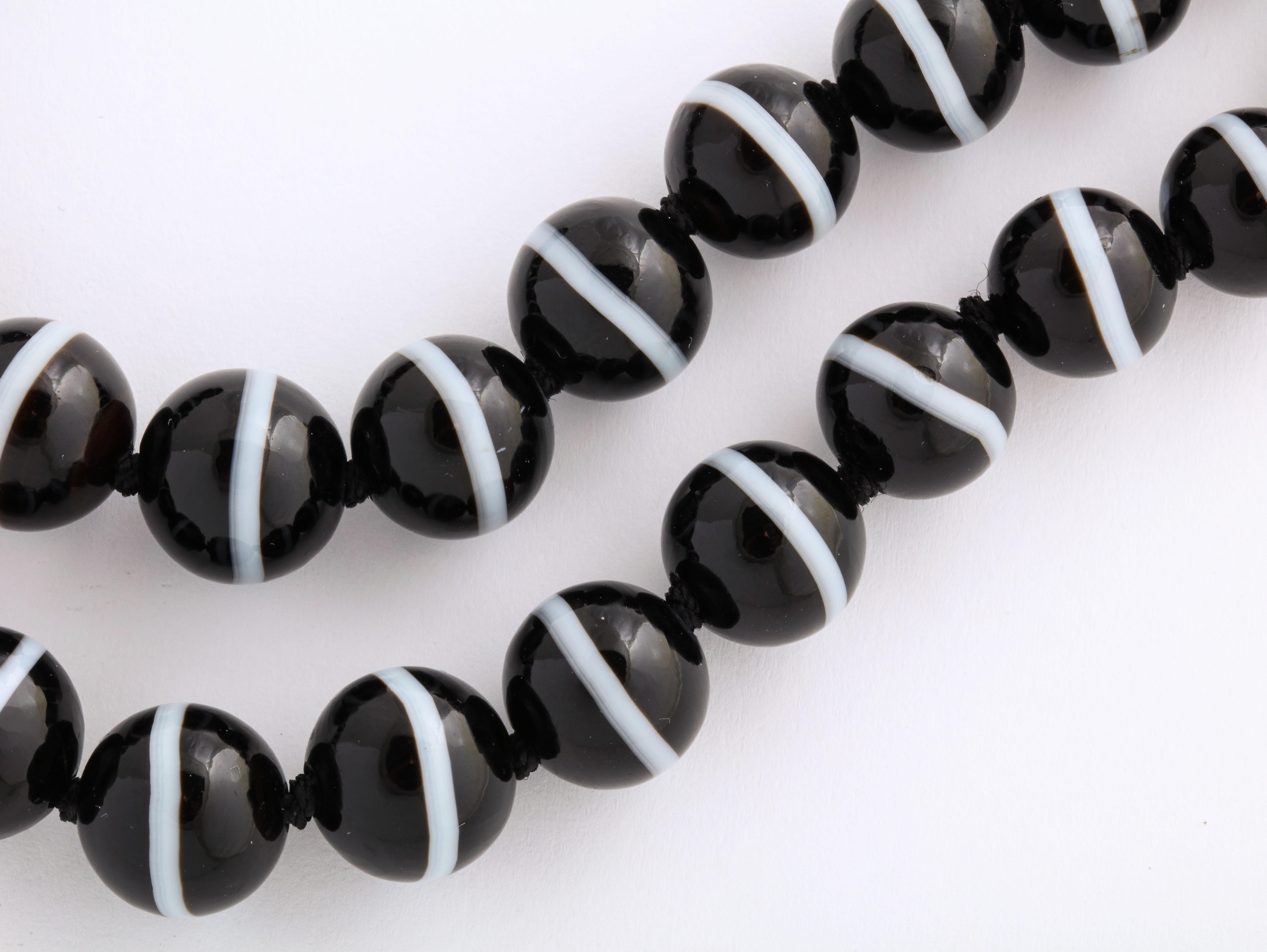 A great, bold beautifully matched strand of banded agate black and white beads from the Victorian Era c. 1860. The banded agate is smooth but the secret is that each bead has facets all over it that were cut and polished by the jewelers hand. Not