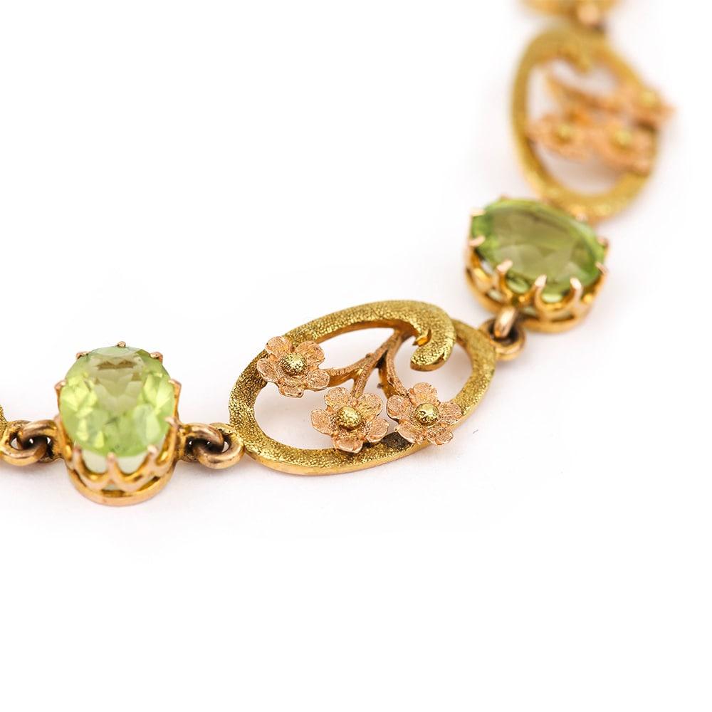 A delightful Victorian peridot bracelet with floral carved 18 karat green, yellow and rose gold panels. Each of the six panels shows a triple rose gold flower with a yellow gold centre, surrounded by a scrolled green gold motif in the Art Nouveau