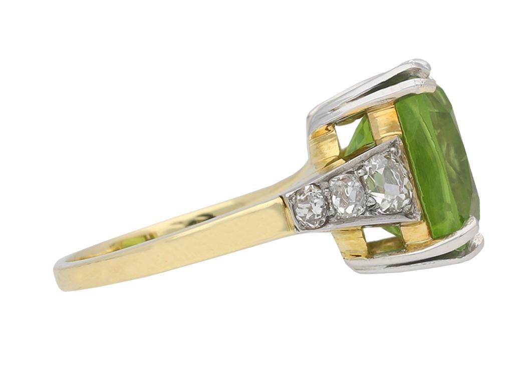 Victorian peridot and diamond ring. Set with one central cushion shape old cut natural unenhanced peridot in an open back split claw setting with an approximate weight of 8.00 carats, flanked by six cushion shape old mine diamonds in open back grain